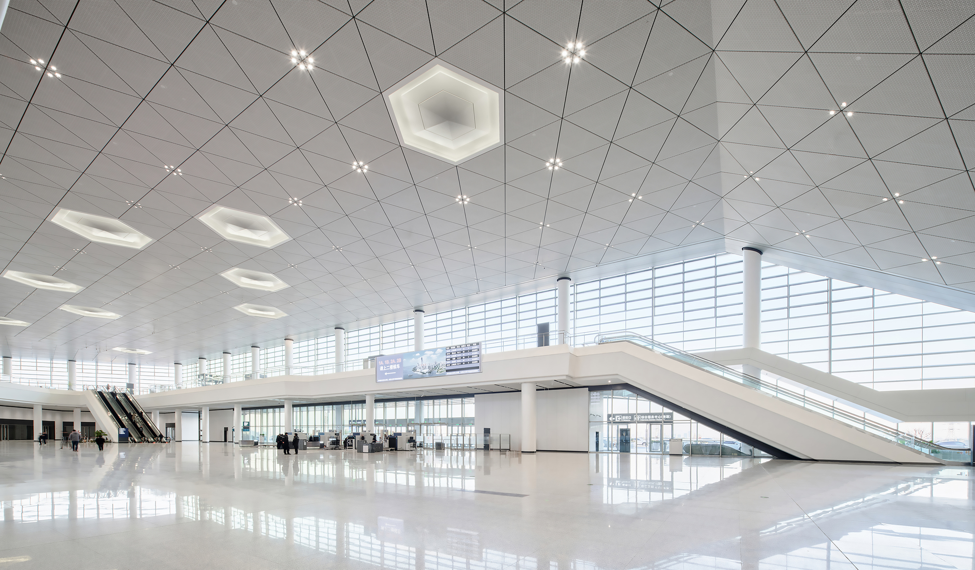 Interior departure hall with white polished floor, triangular ceiling panels and hexagonal skylights
