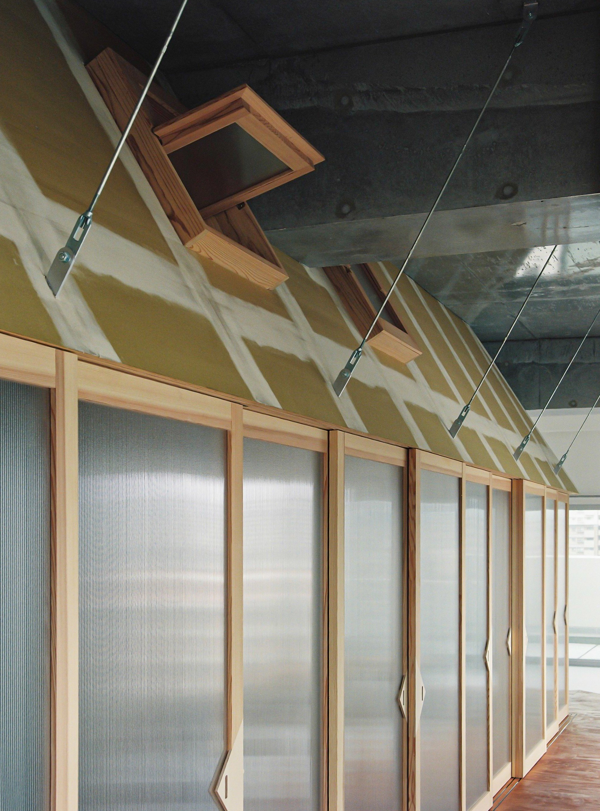 Upward view of the pitched roof structure with skylight opening and tensioned cable supports