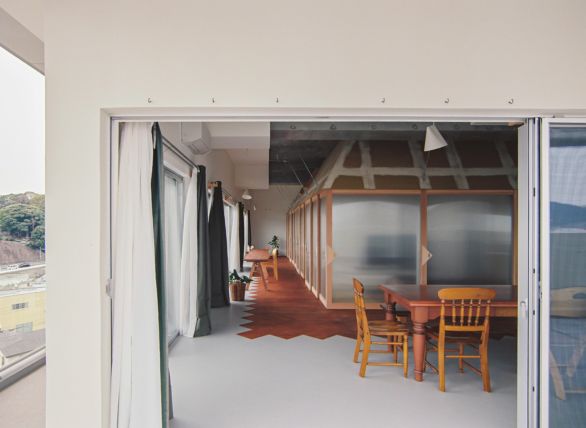 View through sliding door into corridor with timber-framed translucent partitions and dining furniture beyond