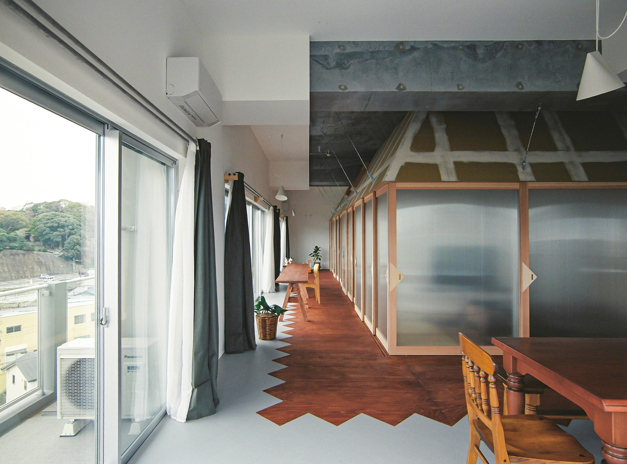 Corridor with zigzag timber flooring, sliding frosted panels, exposed concrete ceiling and full-height glazing with curtains