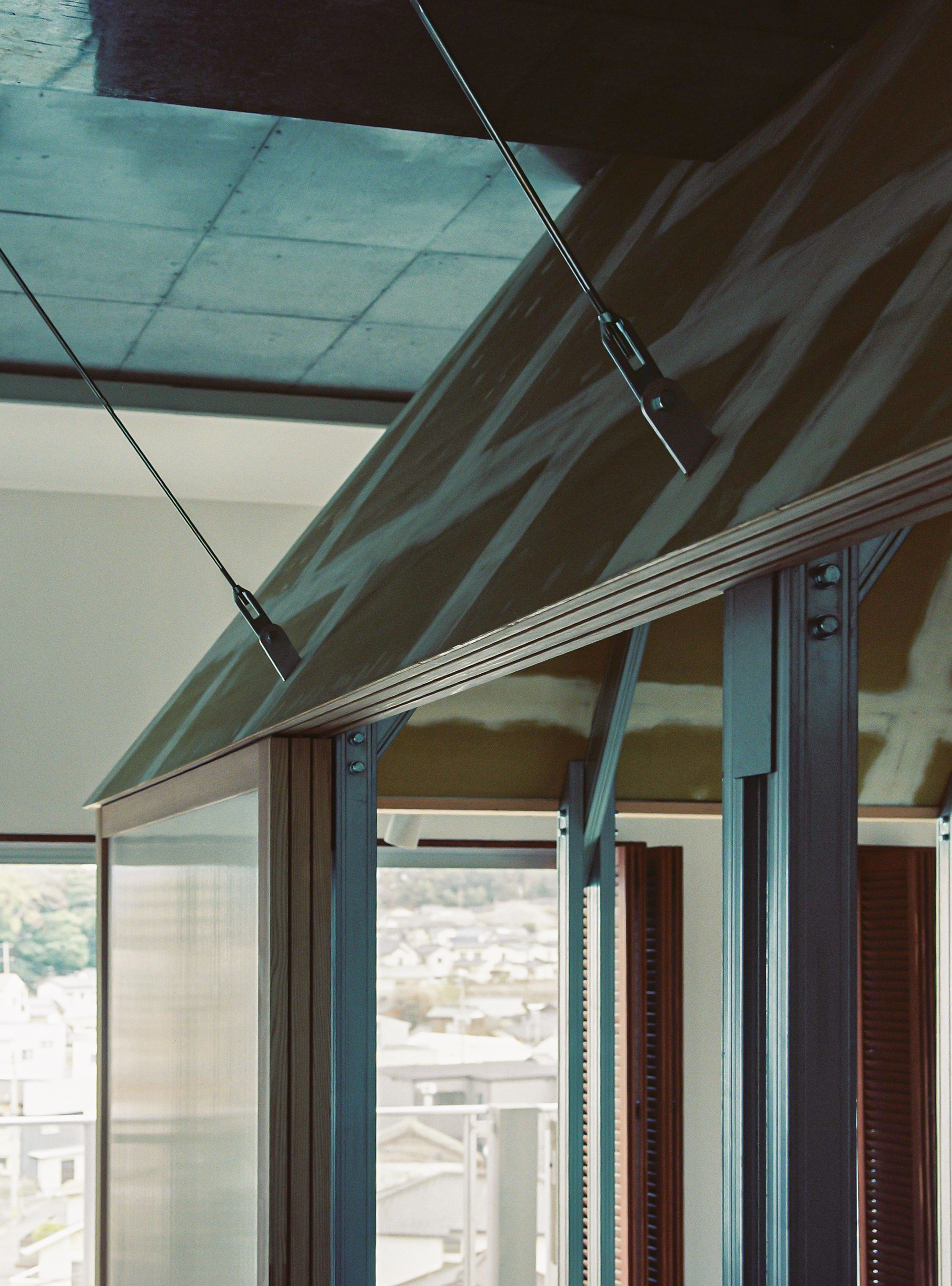 Detail of glass sliding door frame with exposed timber roof trusses and pendant cable above