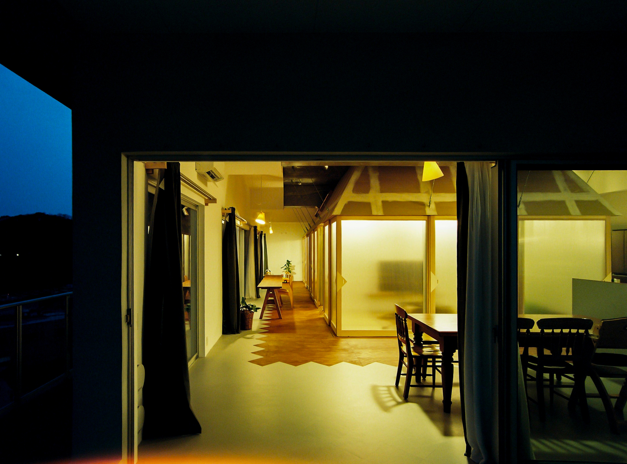 Illuminated interior viewed through open glass doors from exterior terrace at night
