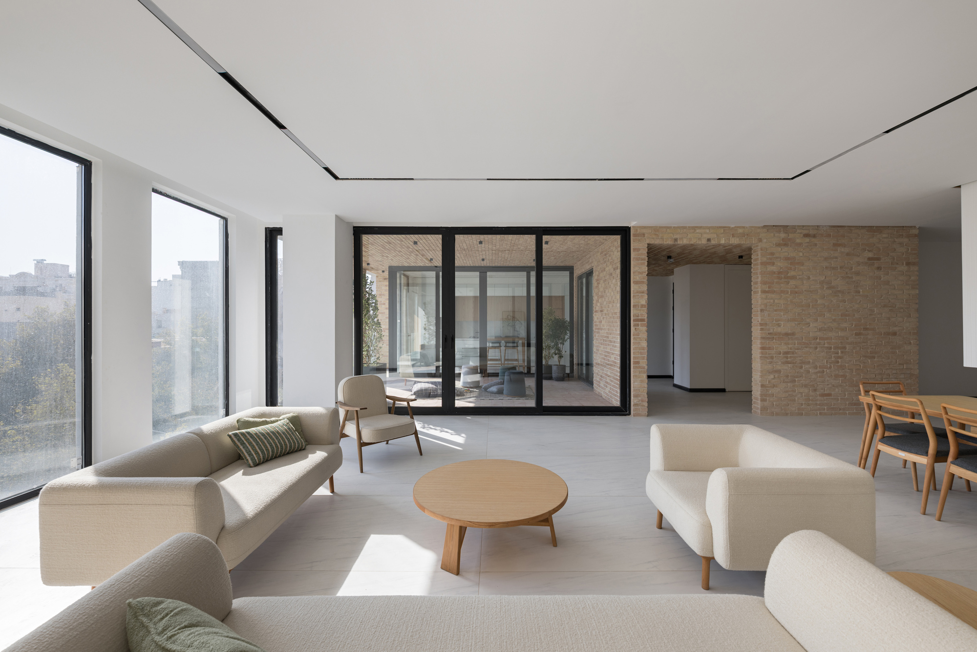 Open plan living space with black-framed glass doors opening onto a timber-lined terrace