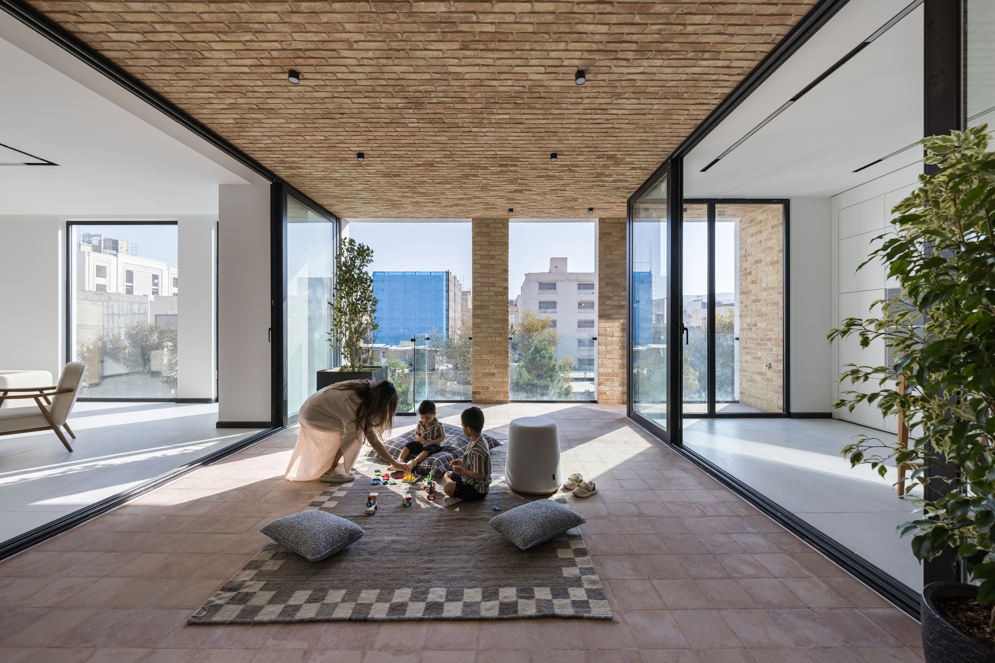 Indoor-outdoor terrace with timber ceiling and two people playing on a patterned rug