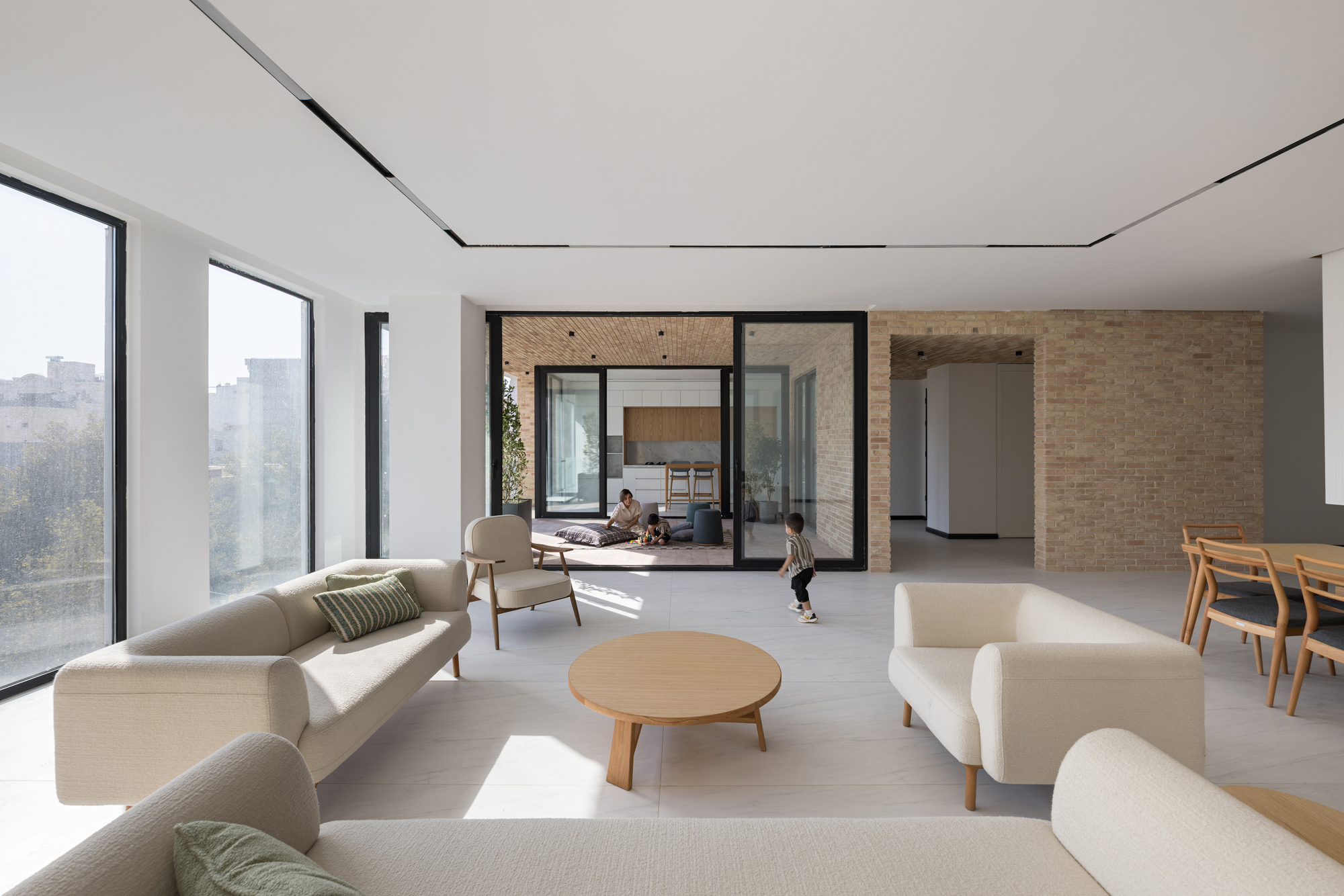 Living area with children playing as sunlight streams through corner windows