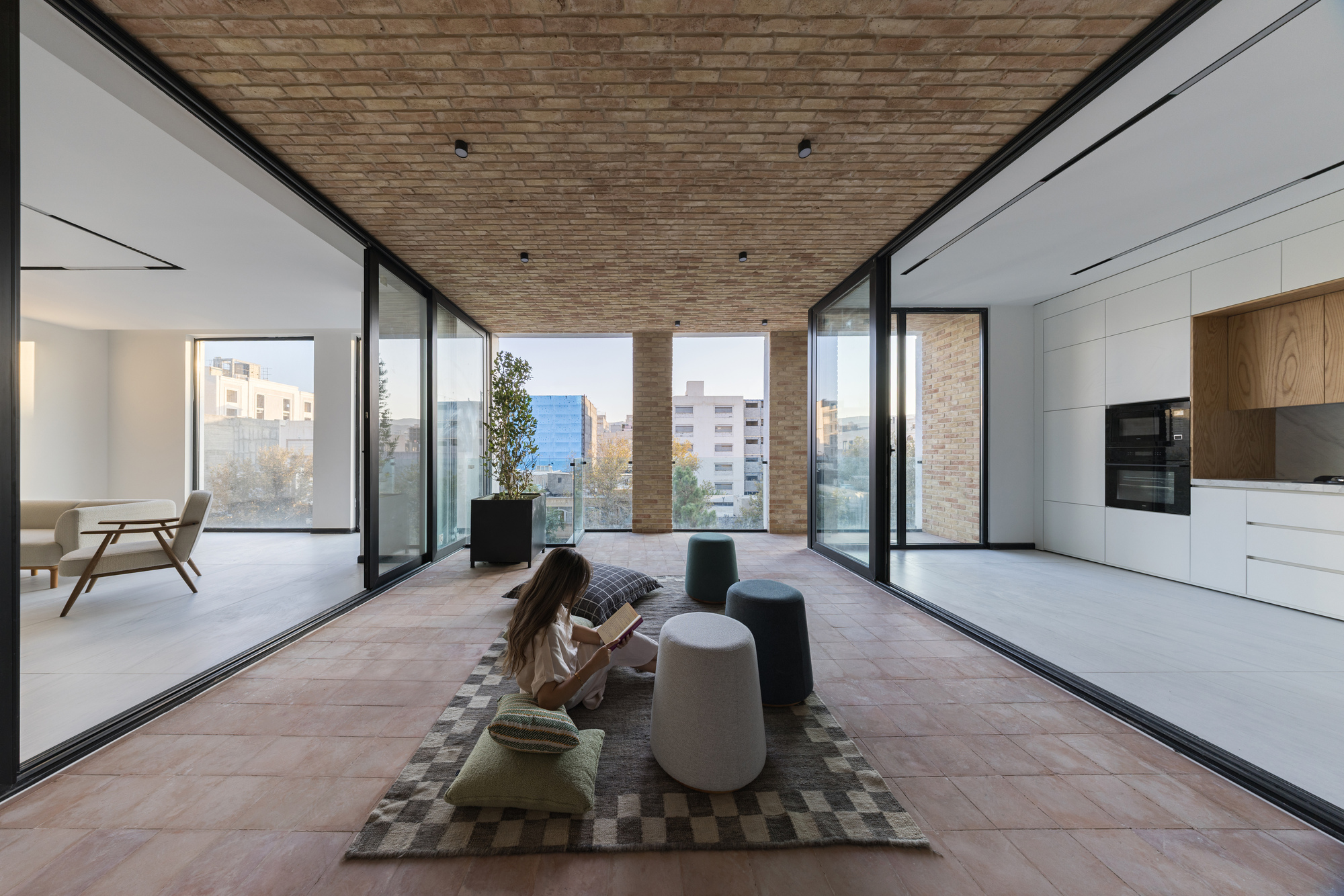 Open-plan interior with terracotta tile floor connecting living spaces and terrace with brick soffit