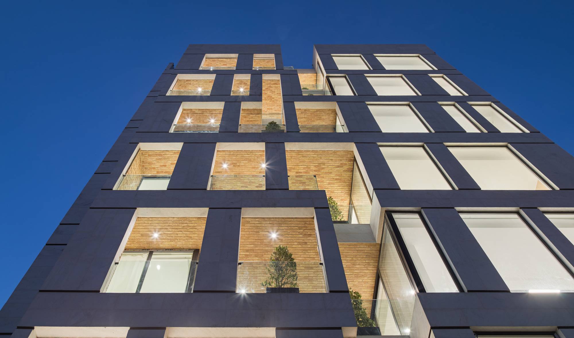 Low angle view of the facade against a clear blue sky showing the grid of openings