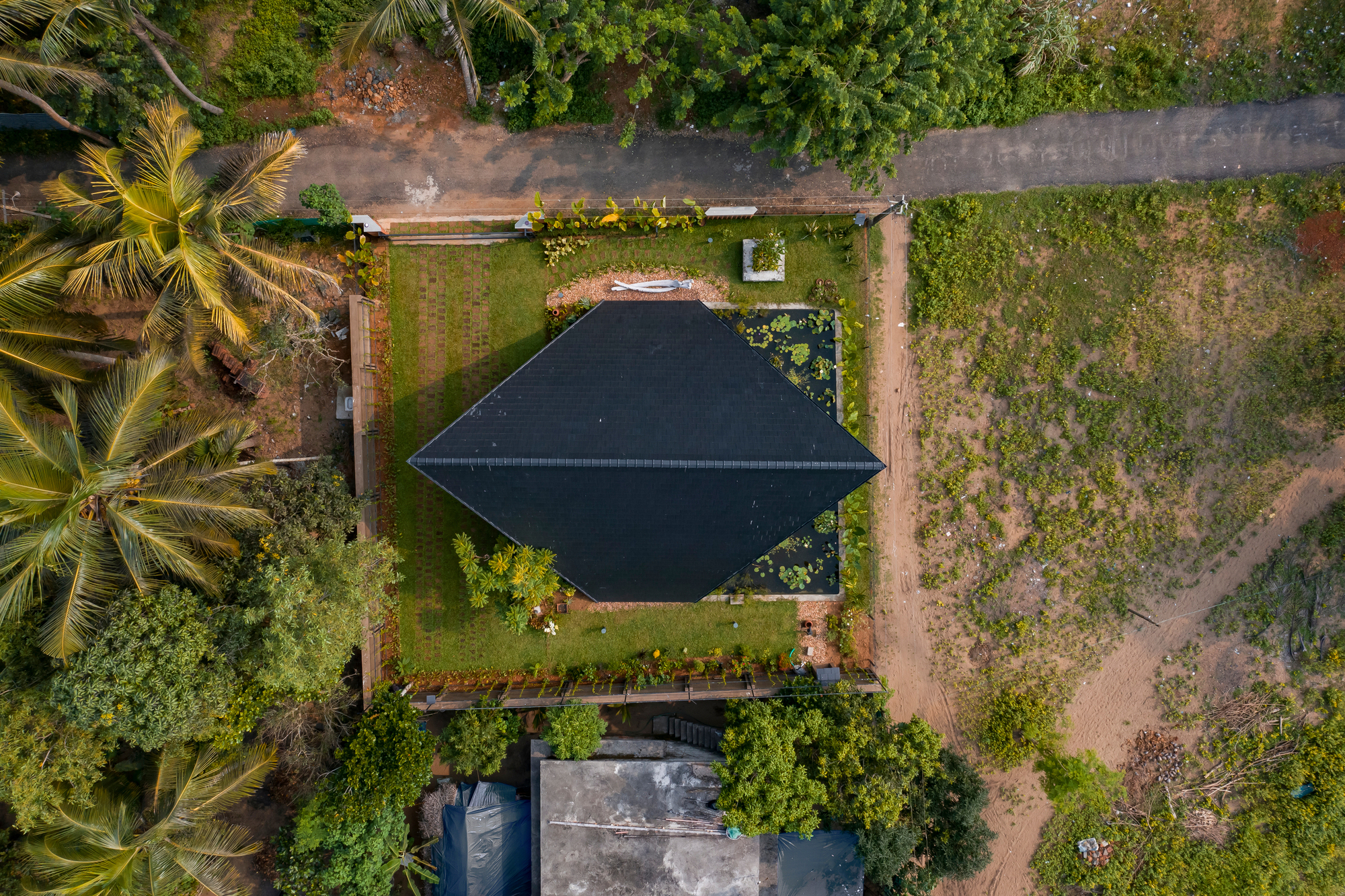 Aerial view of the pyramidal roof nestled among coconut palms and grassy fields