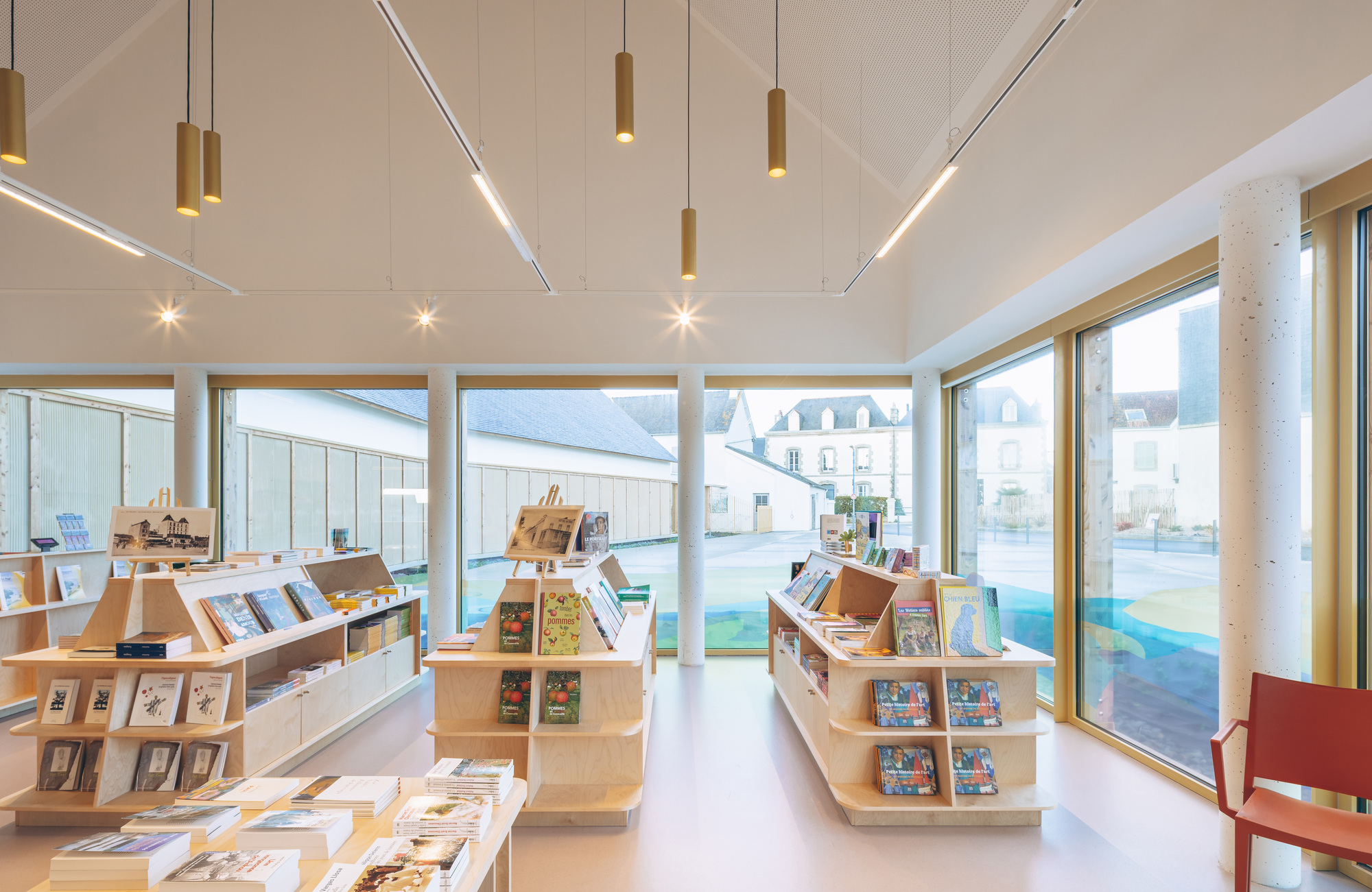 Interior retail space with plywood display shelves beneath linear lighting and timber-framed windows