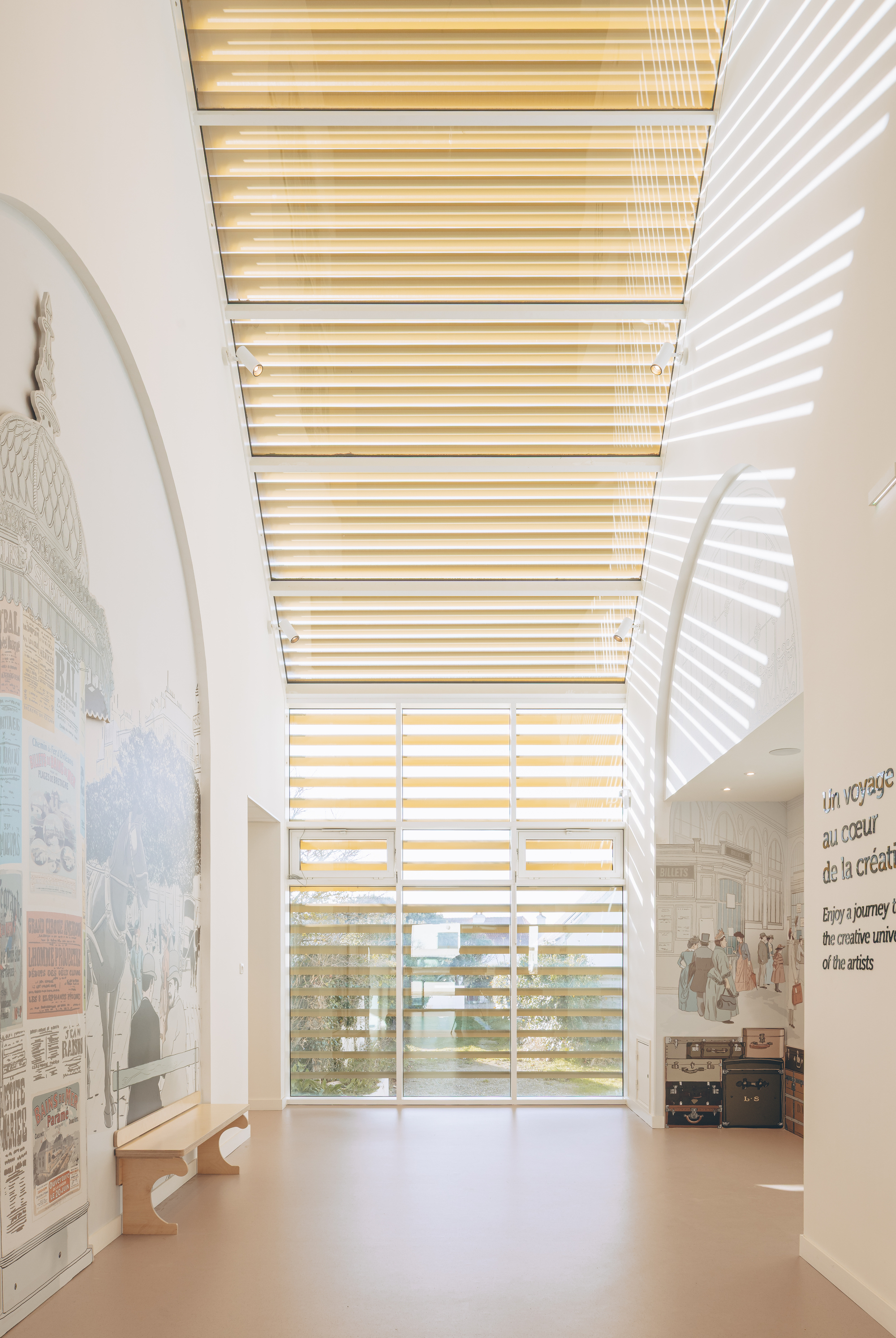 Interior gallery space with horizontal timber louvered skylight casting striped shadows across white walls