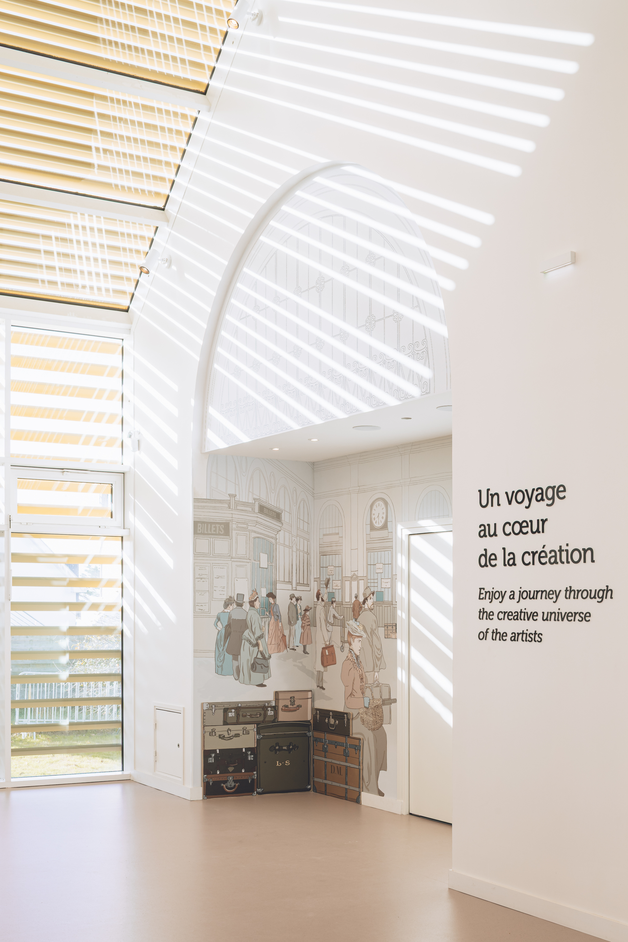 Exhibition wall beneath the louvered skylight with graphic panels and striped light patterns