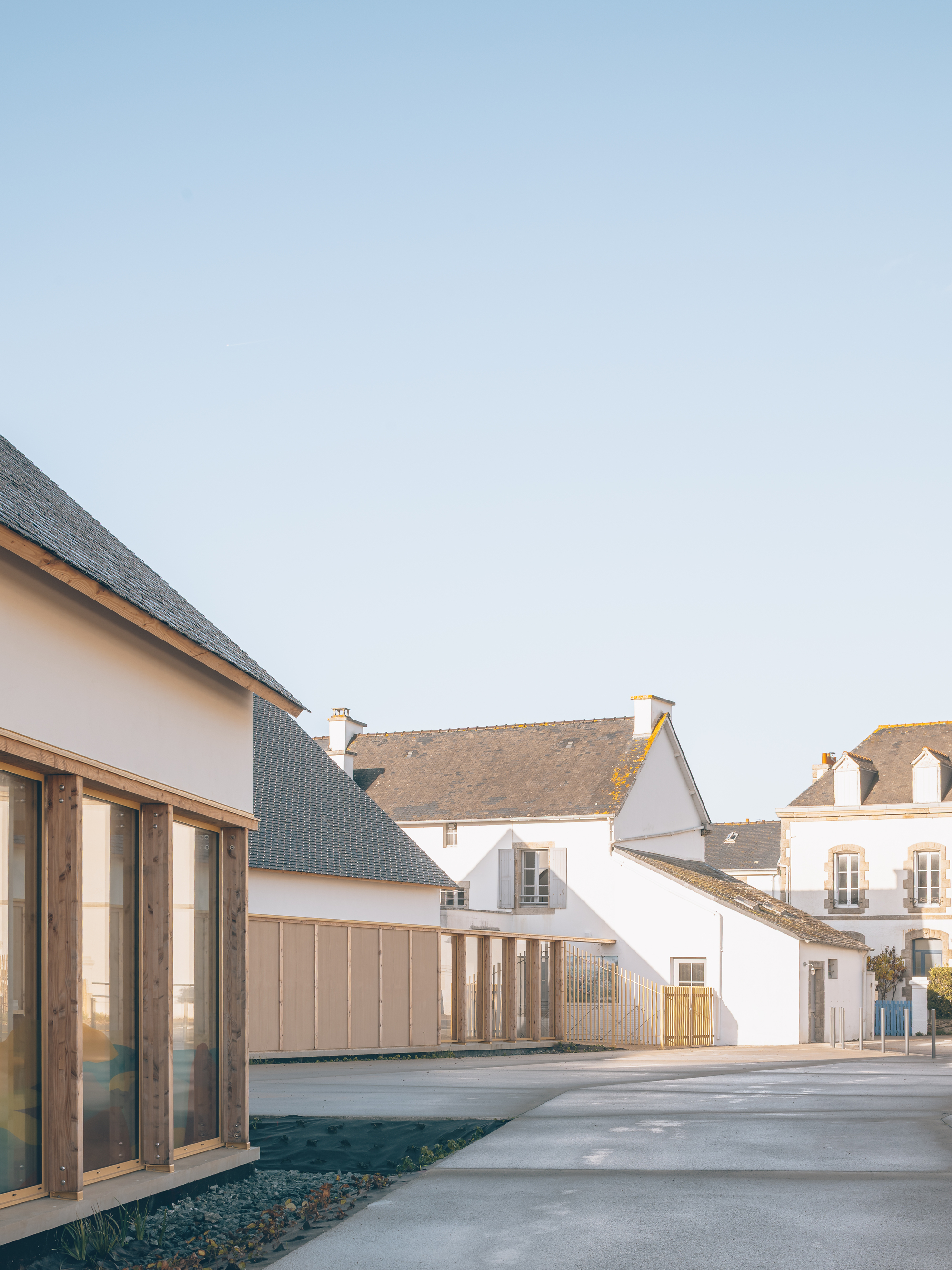 Courtyard view showing gabled volumes with dark slate roofs and timber-clad facades against a clear sky