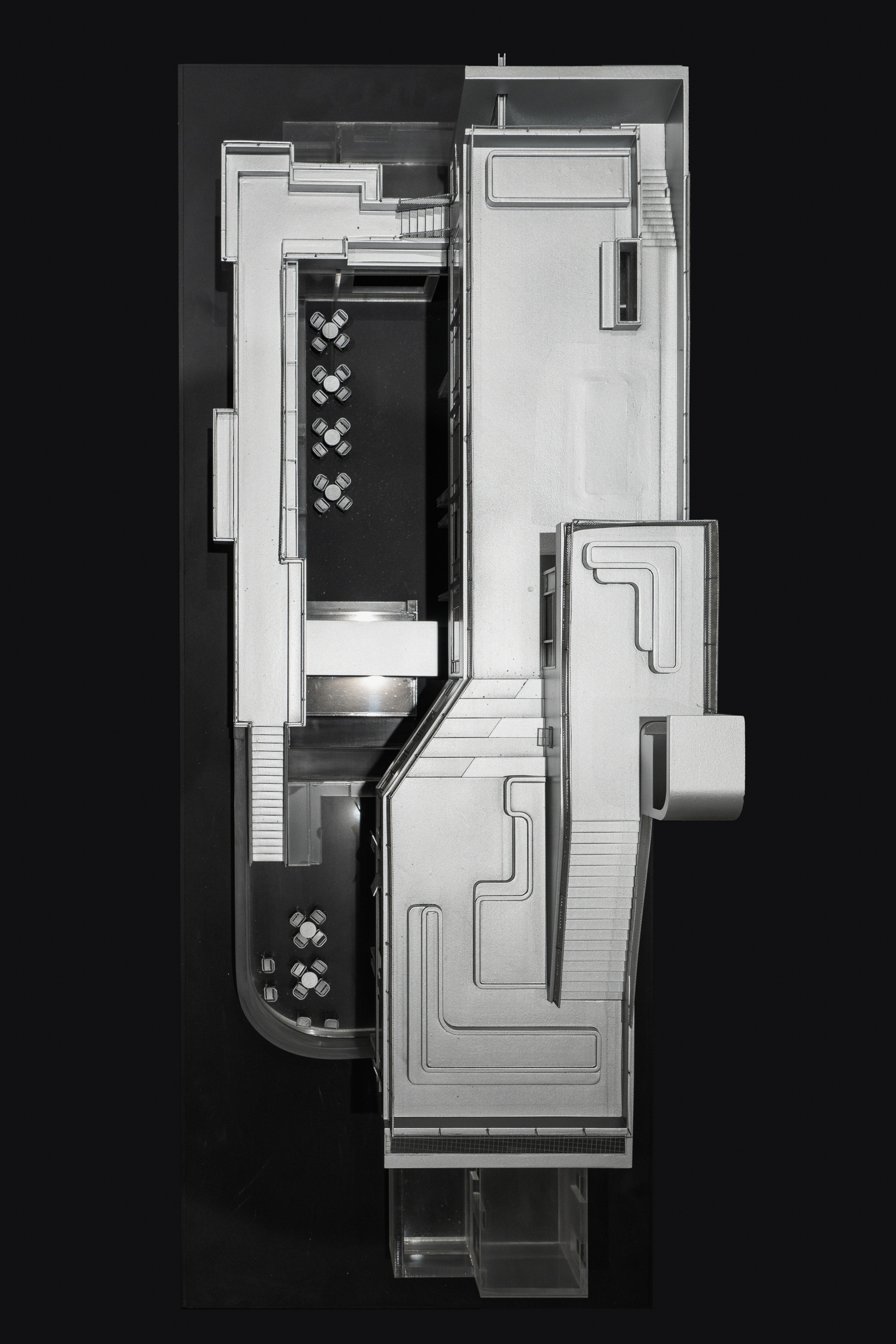 Top-down physical model view showing split-level interior spaces with two dining areas and stairs