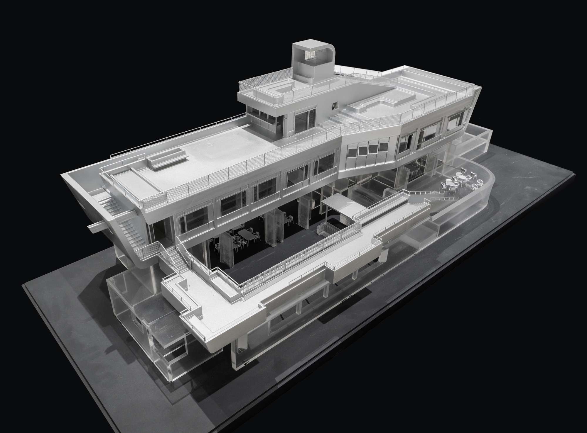 Physical model in angled view revealing layered horizontal terraces and a cylindrical rooftop element