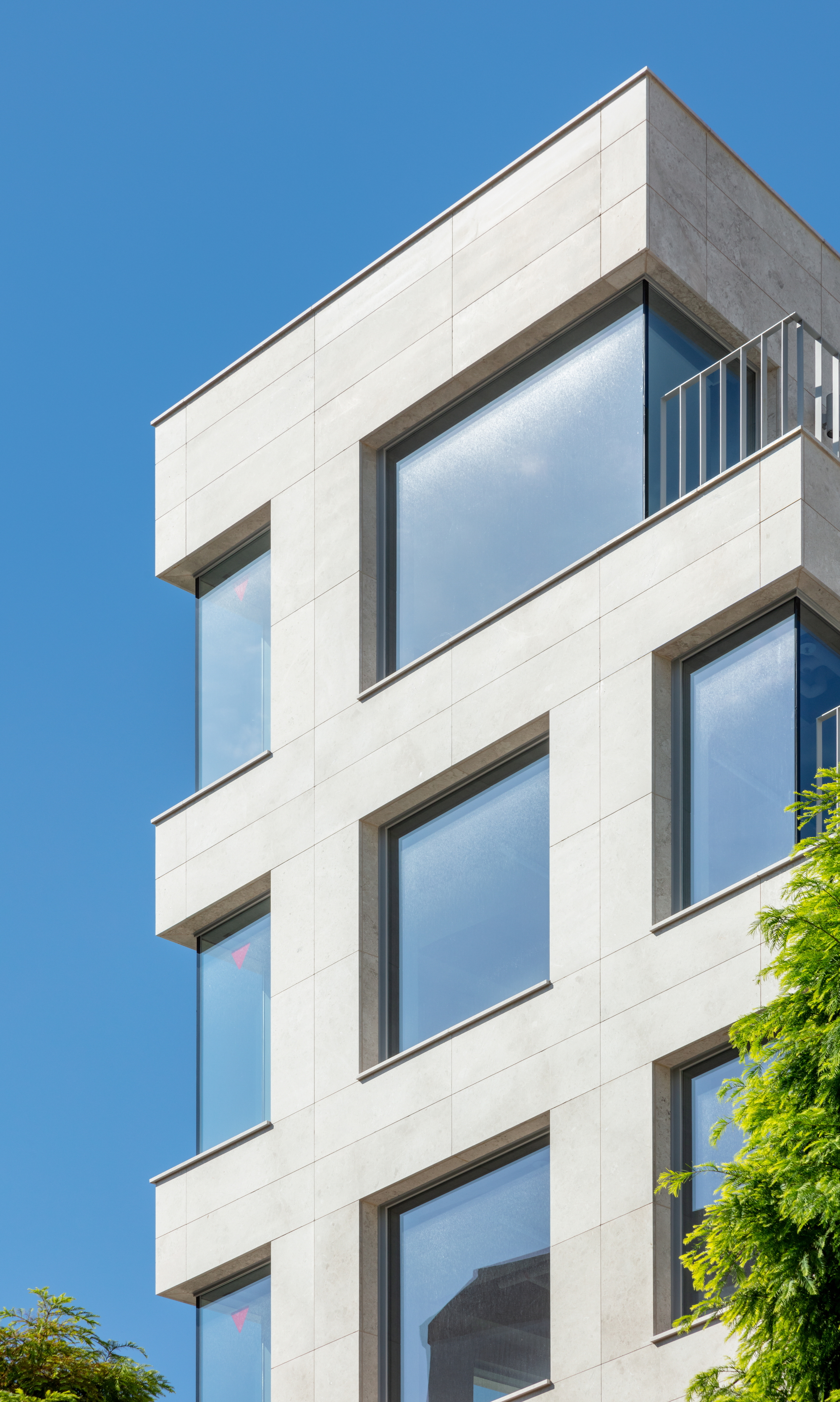 Close-up of the stacked window openings with recessed frames in white stone cladding