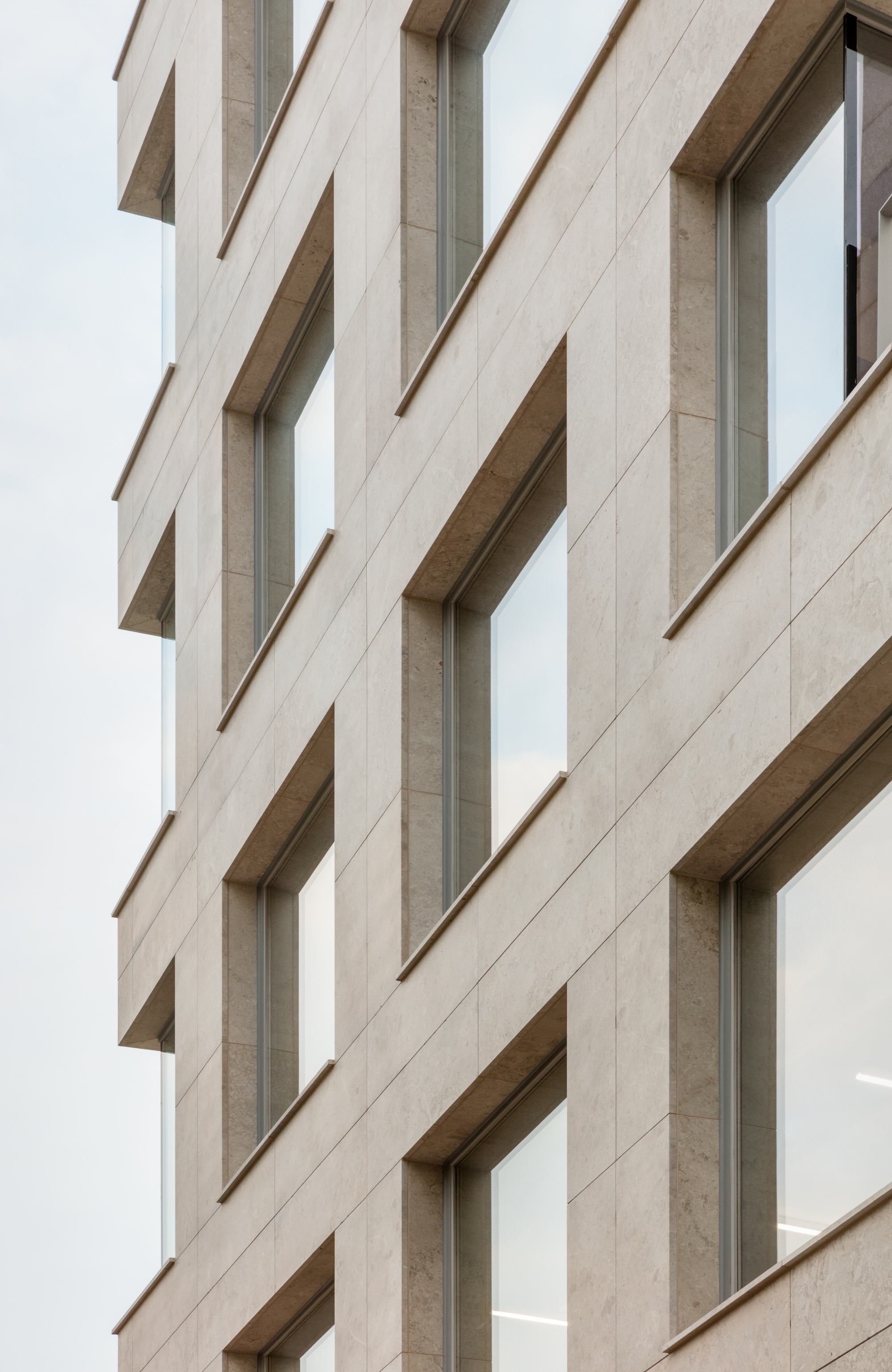 Facade detail showing the vertical rhythm of recessed windows in pale stone panels