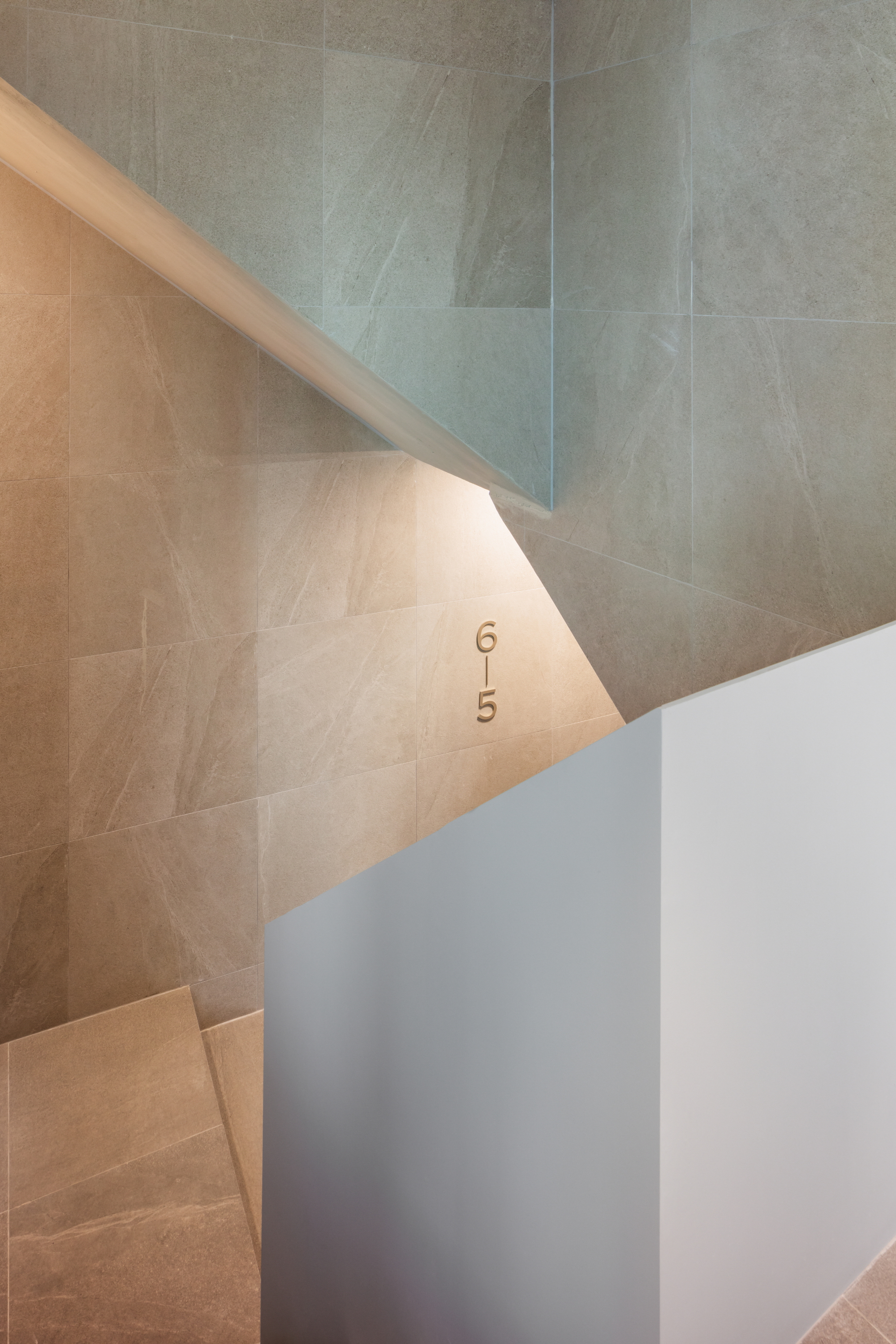 Downward view into the tiled stairwell showing angular walls and floor number markings