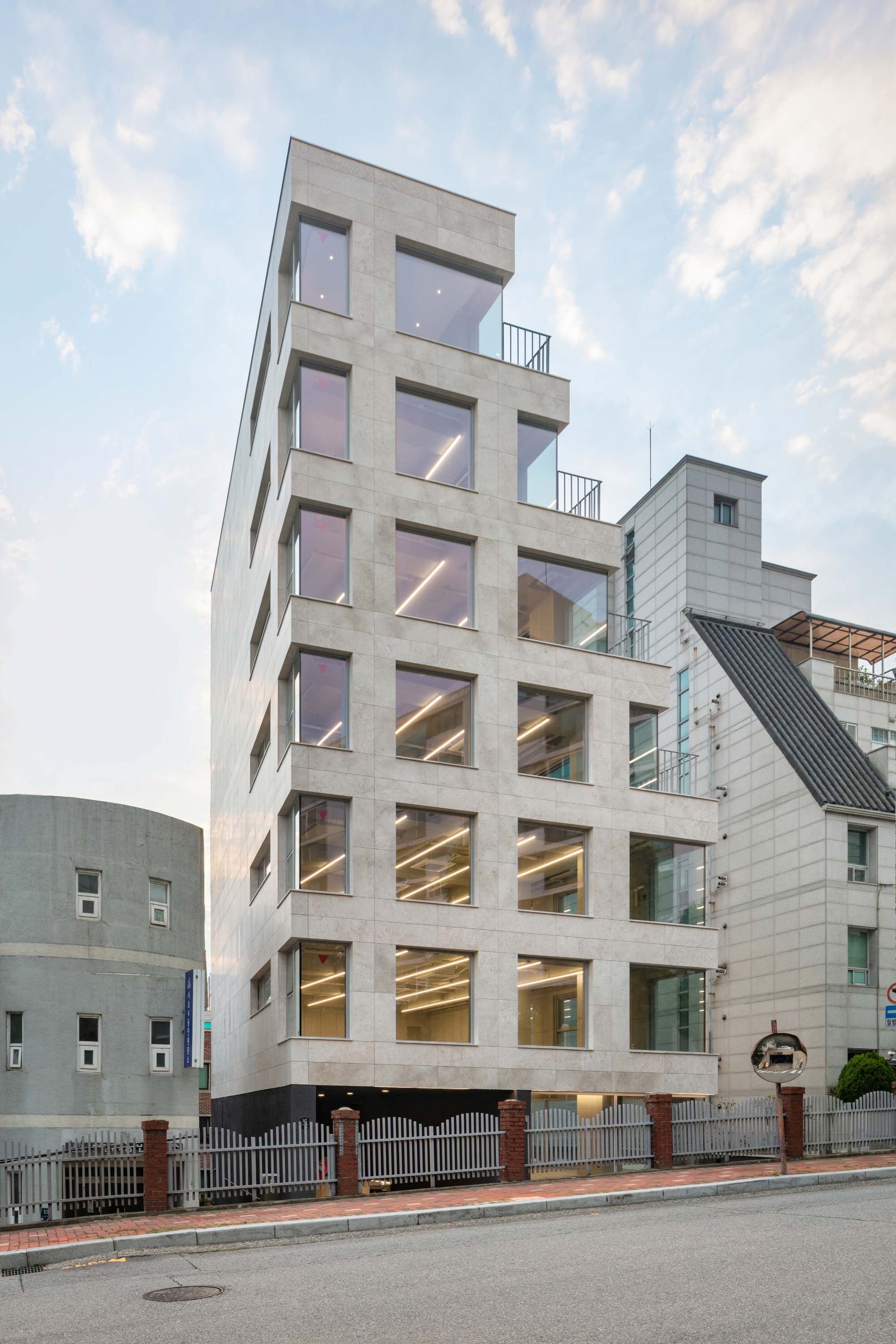 Six-story concrete facade with recessed balconies and warm interior lighting at twilight