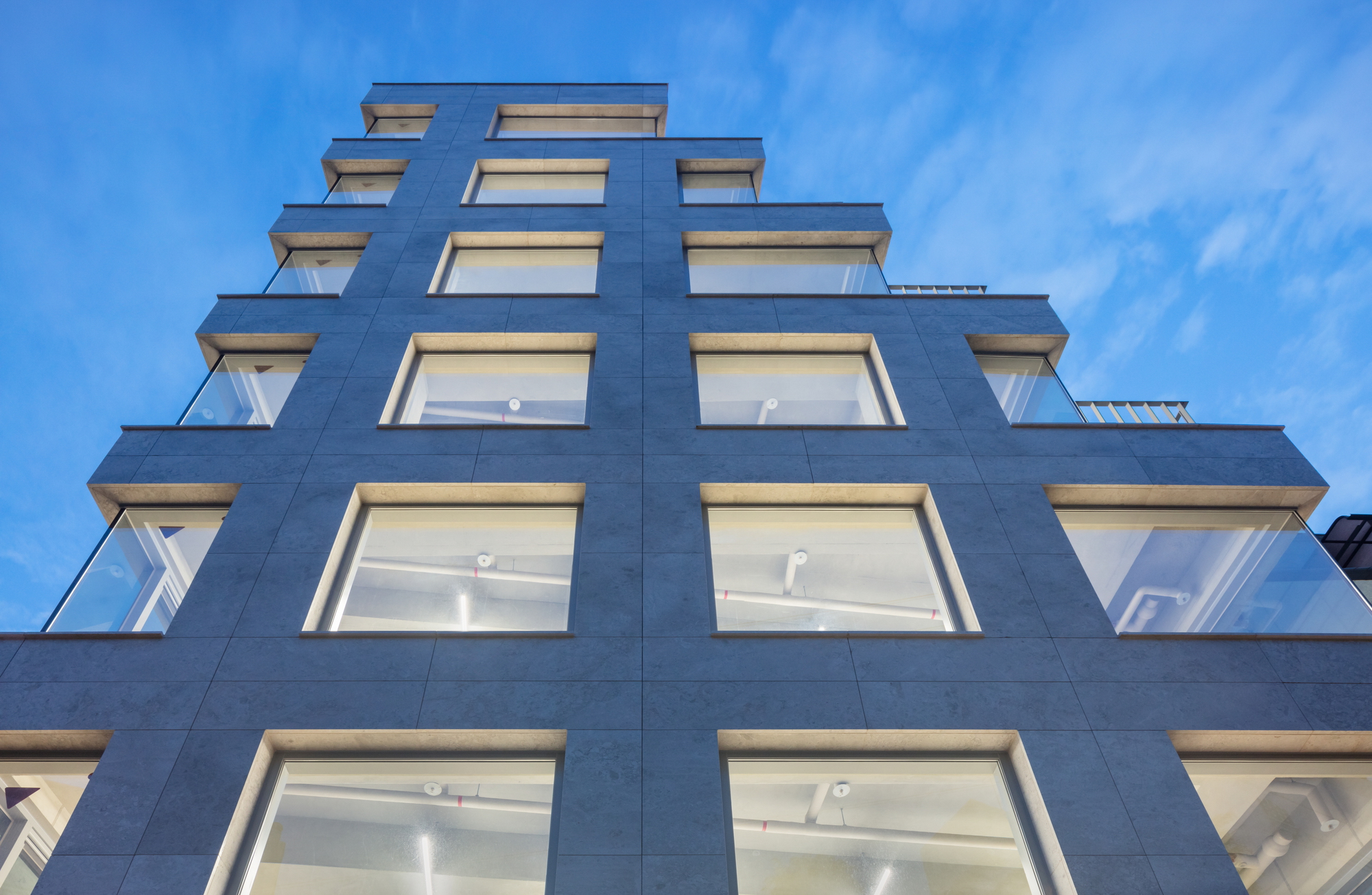 Upward view of the stepped facade with recessed balconies and horizontal window bands