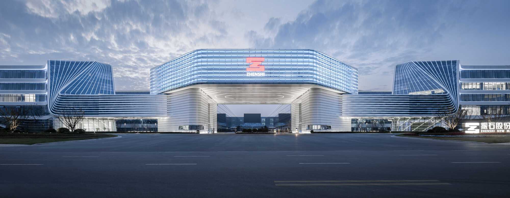 Symmetrical entrance portal with horizontal louvers and illuminated canopy beneath dramatic clouds