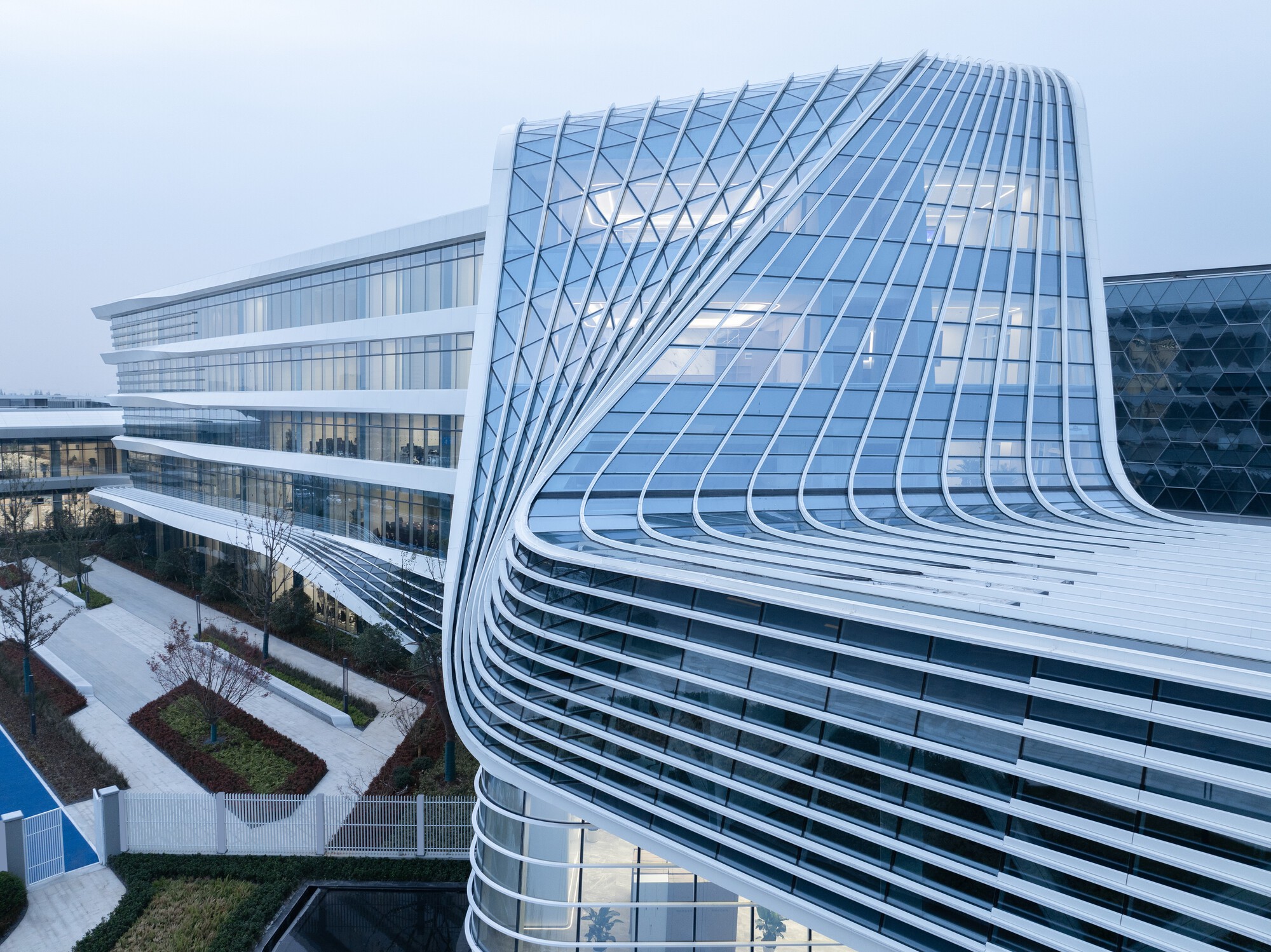 Corner detail of the curved glass curtain wall with diagonal patterning at twilight