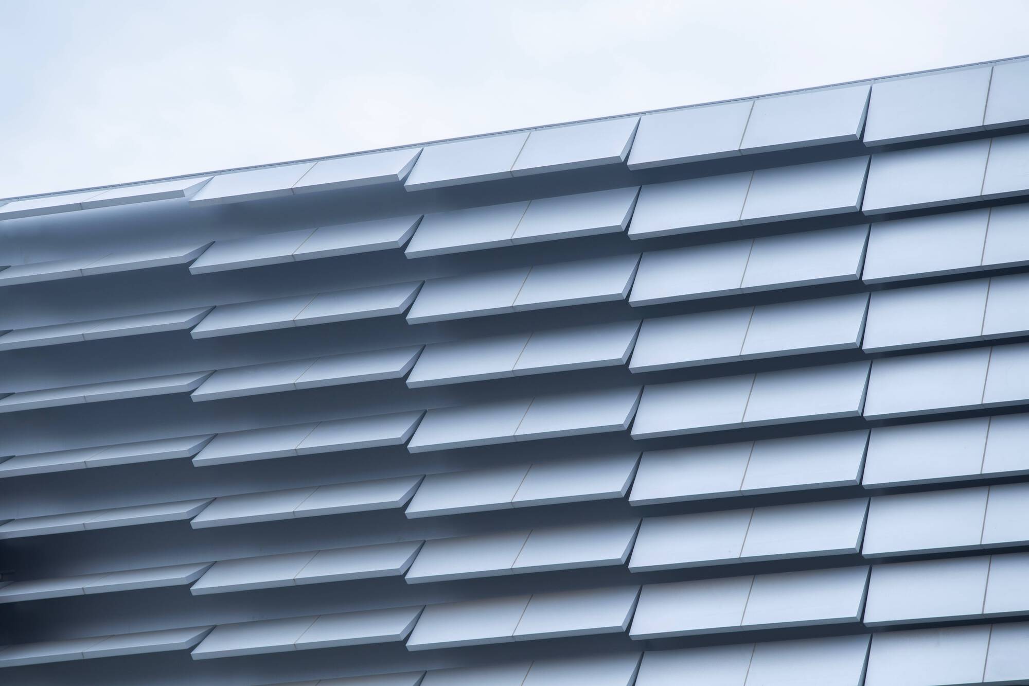 Close-up of the folded aluminum panel cladding system with horizontal shadow lines