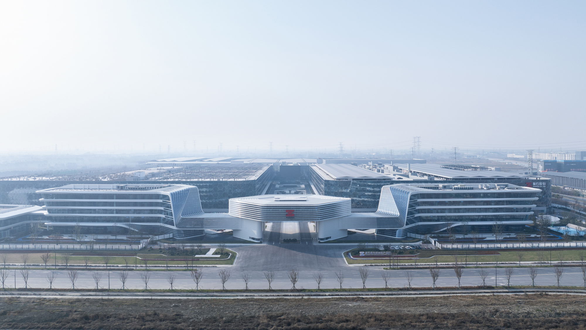 Distant view of the symmetrical campus with horizontal facades and central bridge in hazy conditions
