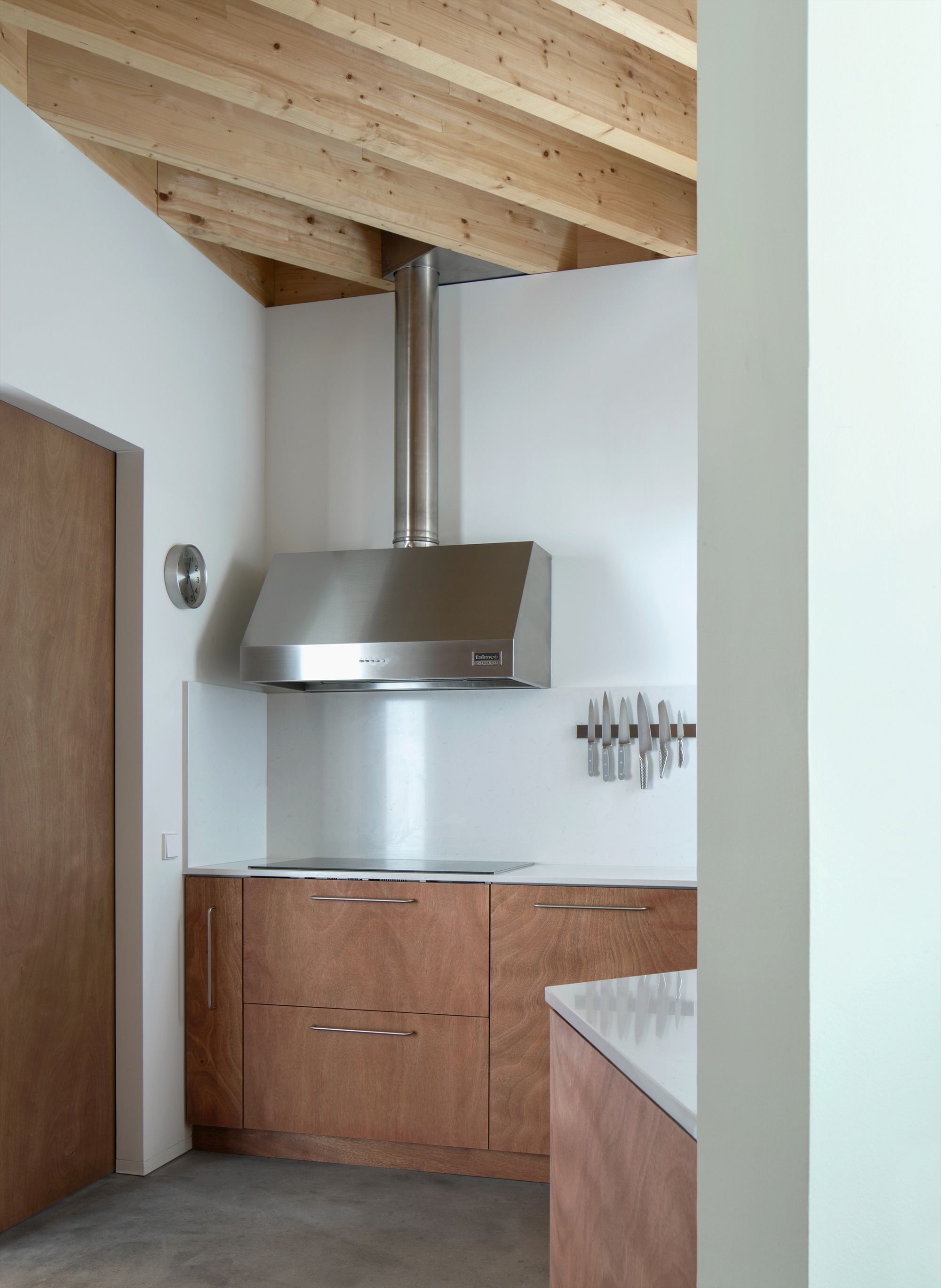 Kitchen corner with stainless steel range hood beneath exposed timber beams and white walls