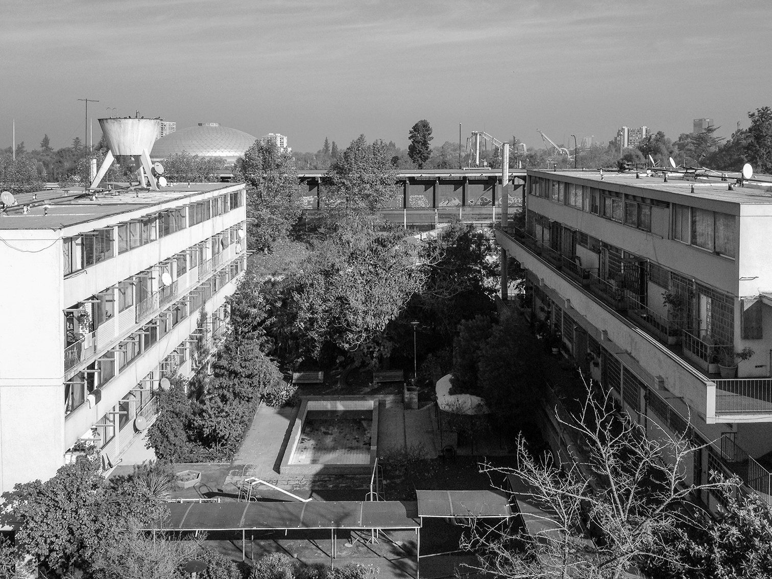 Elevated view of the courtyard between two linear residential blocks with mature trees and a water tower beyond