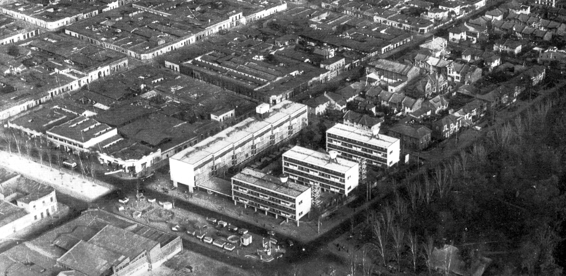 Aerial view showing three parallel residential slabs within a grid of surrounding housing and gardens