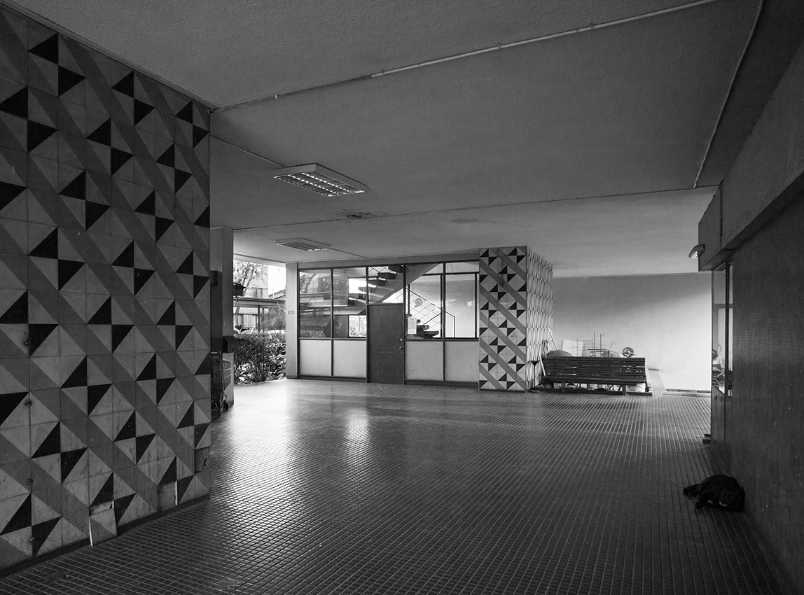 Entry lobby with pyramidal relief wall panel and glazed doors leading to an interior staircase