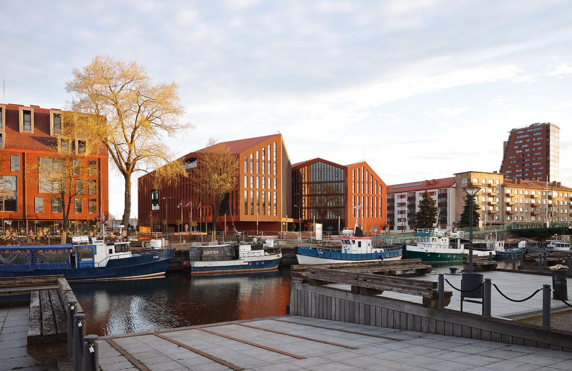 Waterfront view of the complex from the harbor with moored boats and adjacent residential towers