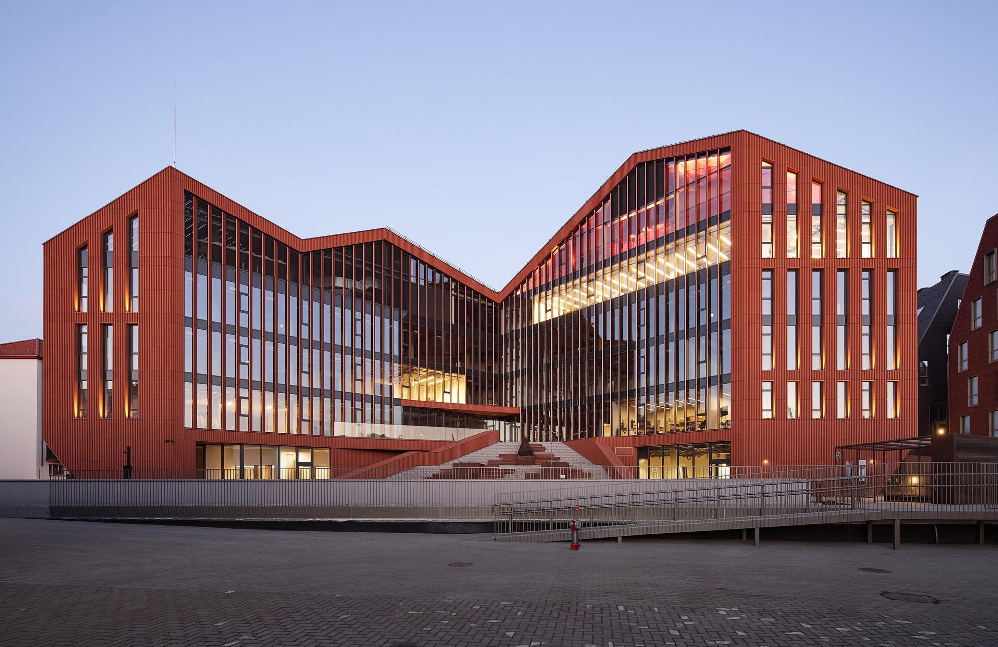 Courtyard elevation showing interlocking volumes with illuminated vertical glazing at twilight