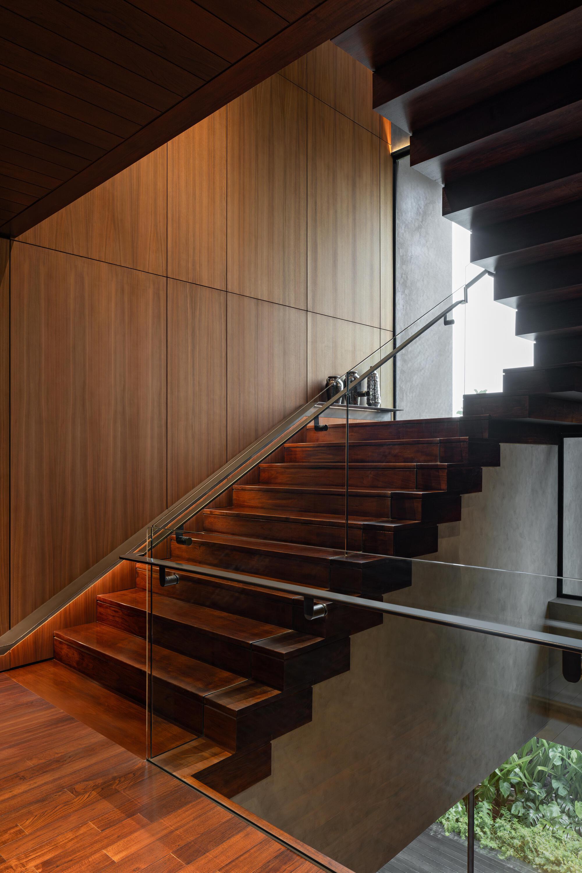View up the timber and concrete stairwell with glass railing under timber ceiling