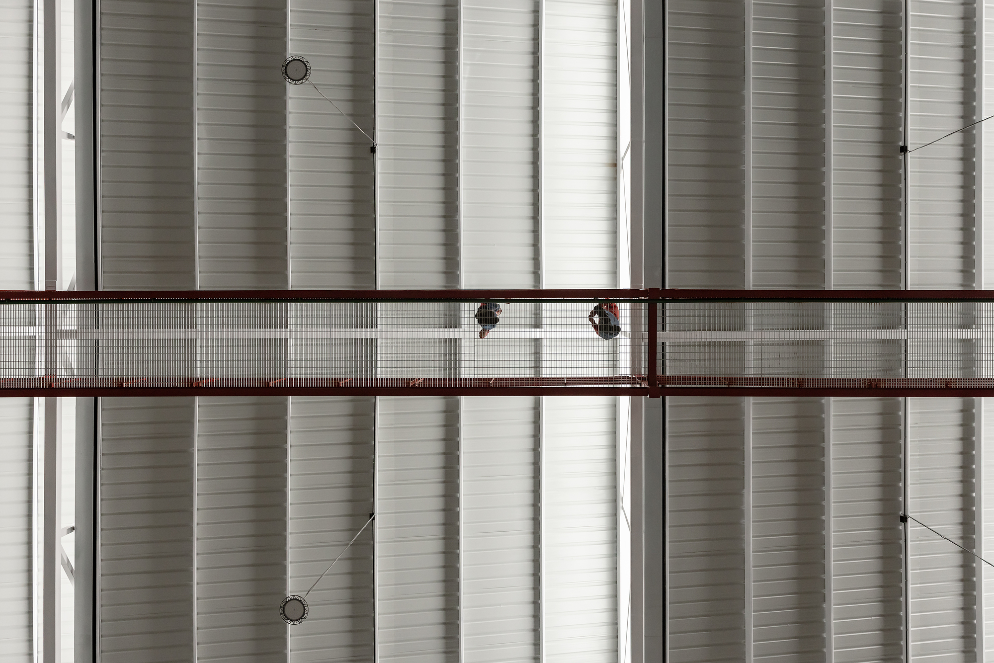 Close-up of horizontal corrugated metal cladding with two red-framed walkways crossing at different levels