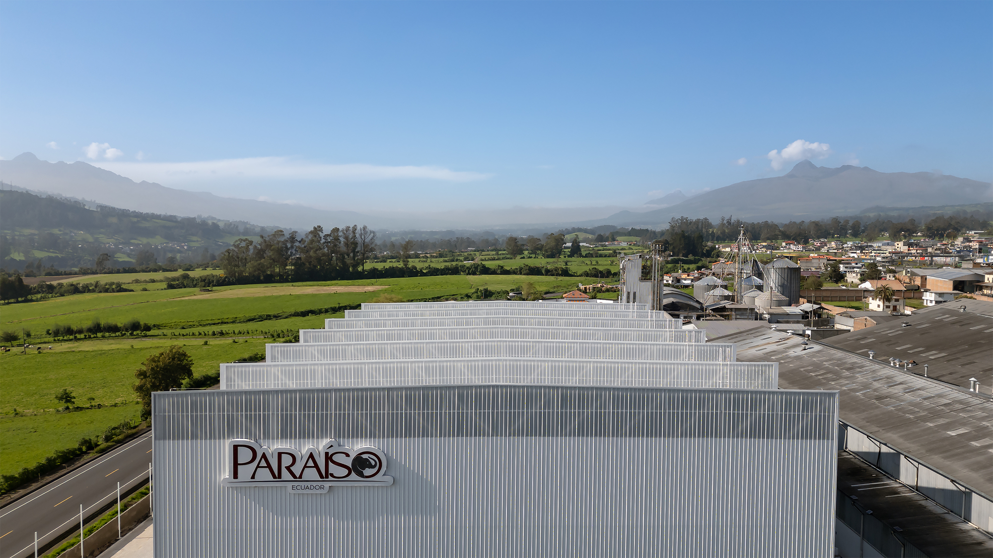 Drone view of the stepped corrugated metal roof volumes against a valley landscape with scattered clouds
