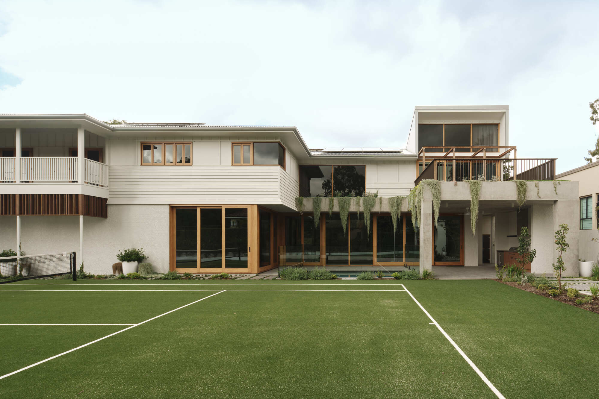 Rear garden view with horizontal weatherboard cladding and timber-framed glazing across linked volumes