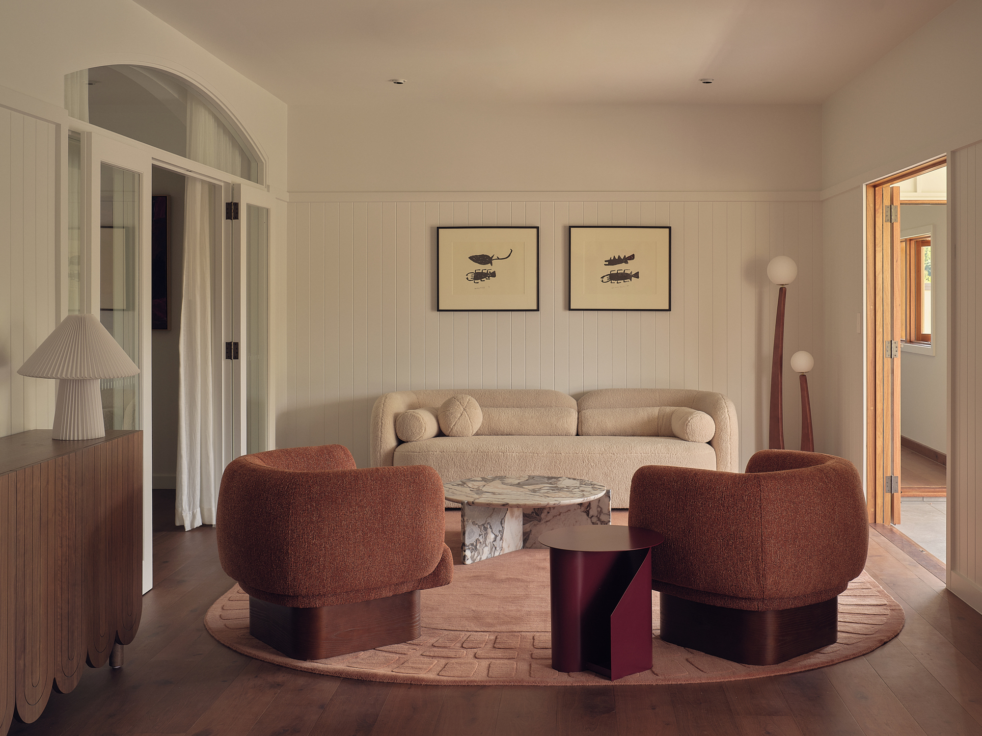 Living room with vertical paneling, curved seating, and warm afternoon light through arched doorway
