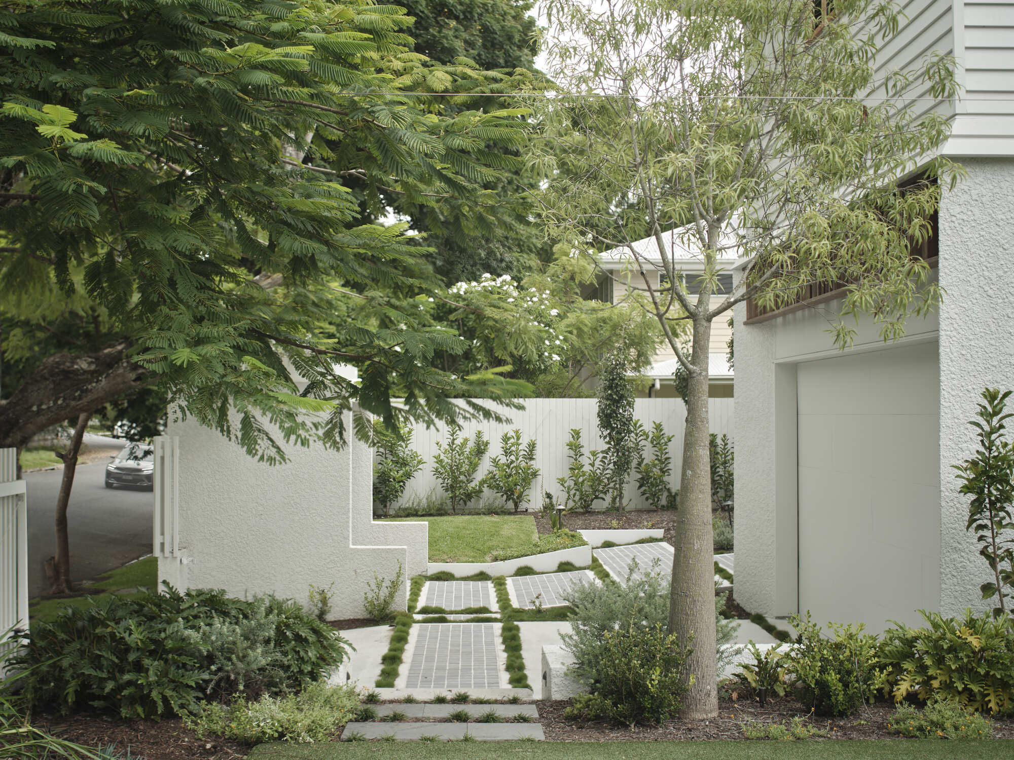 Front garden entry path with stepping stones running between planted beds and mature trees