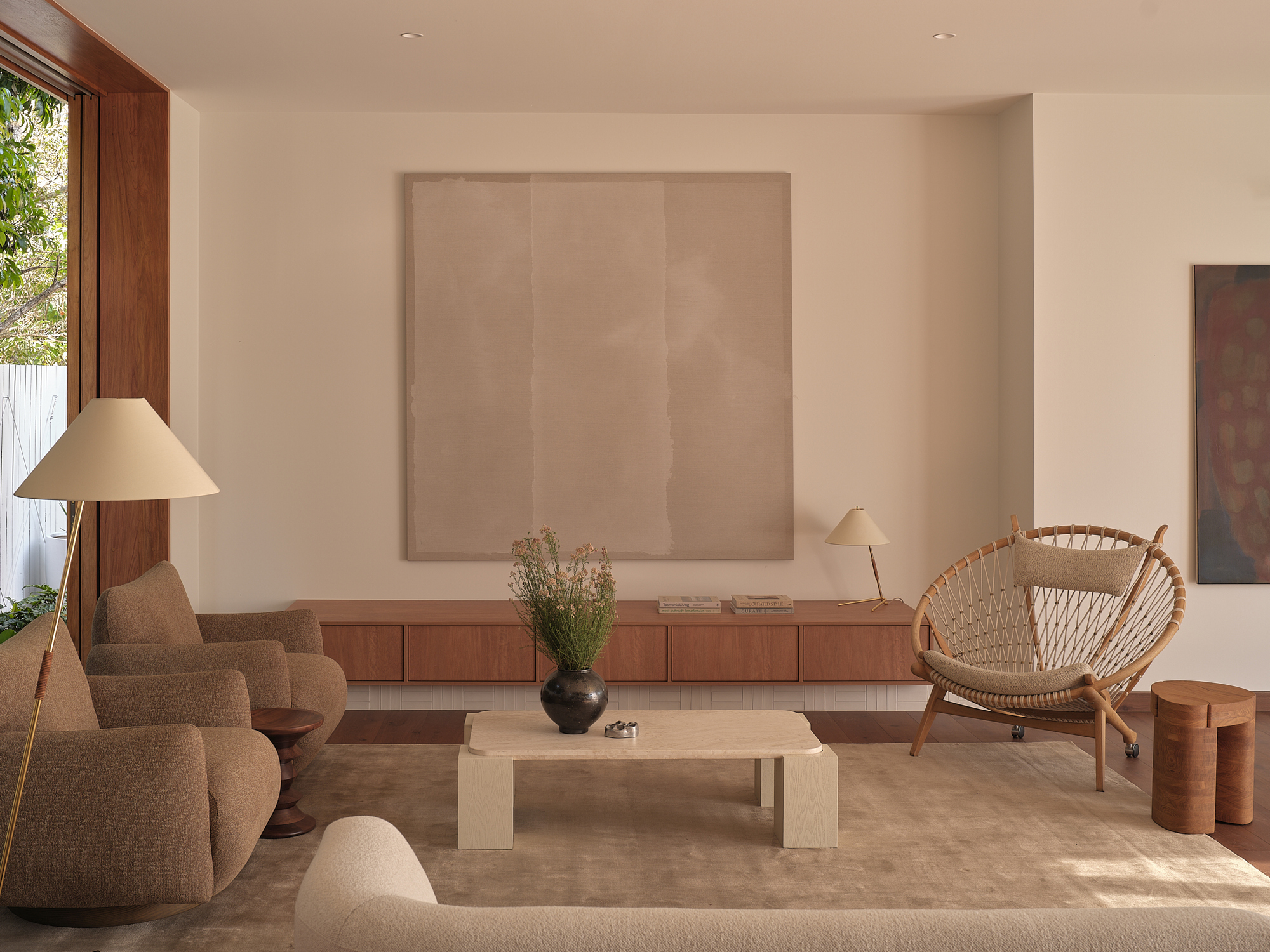 Living room with floor lamp, low timber cabinetry and large canvas hanging on the white wall