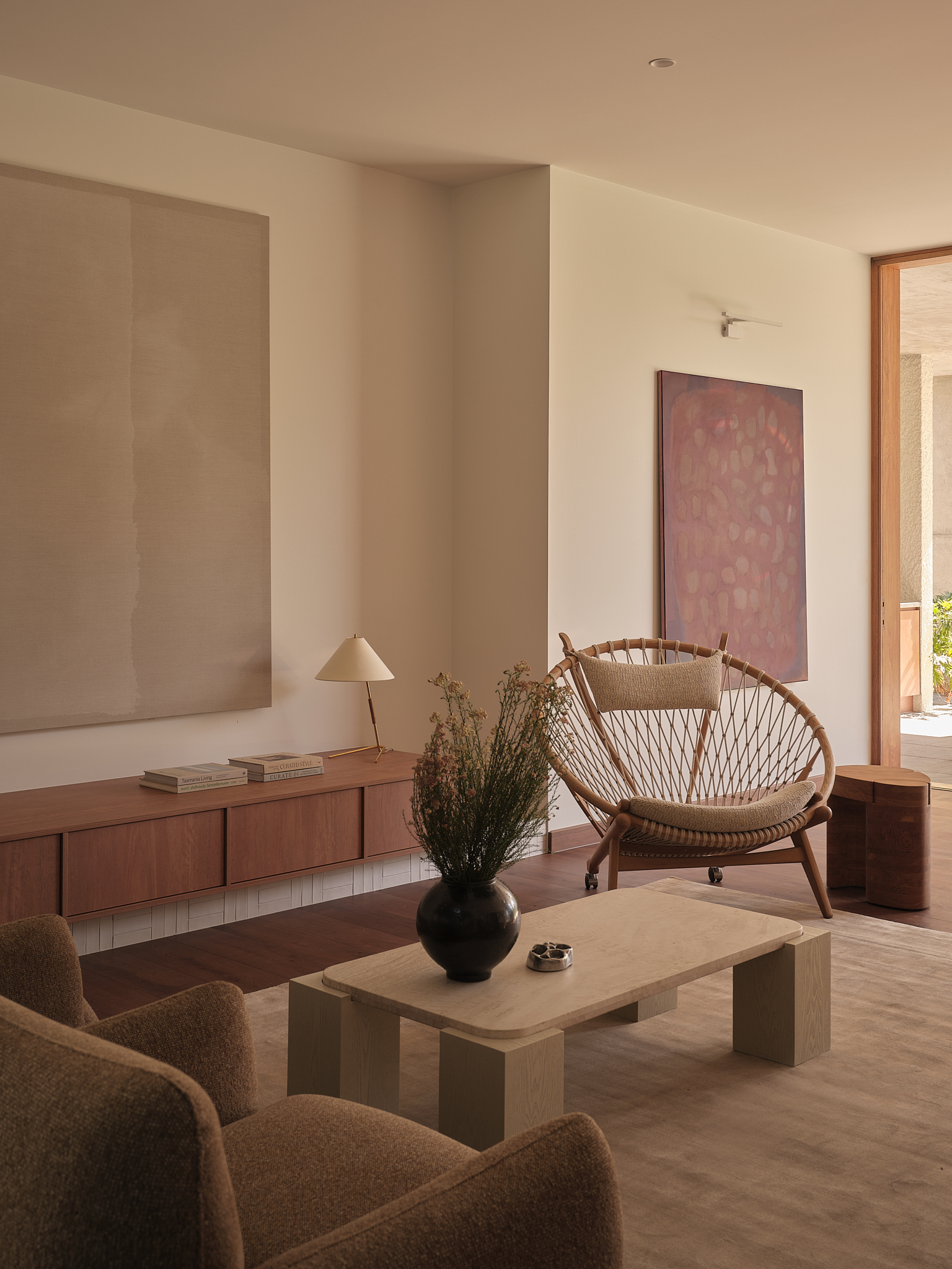 Seating area with timber credenza beneath recessed wall panel and open doorway to garden