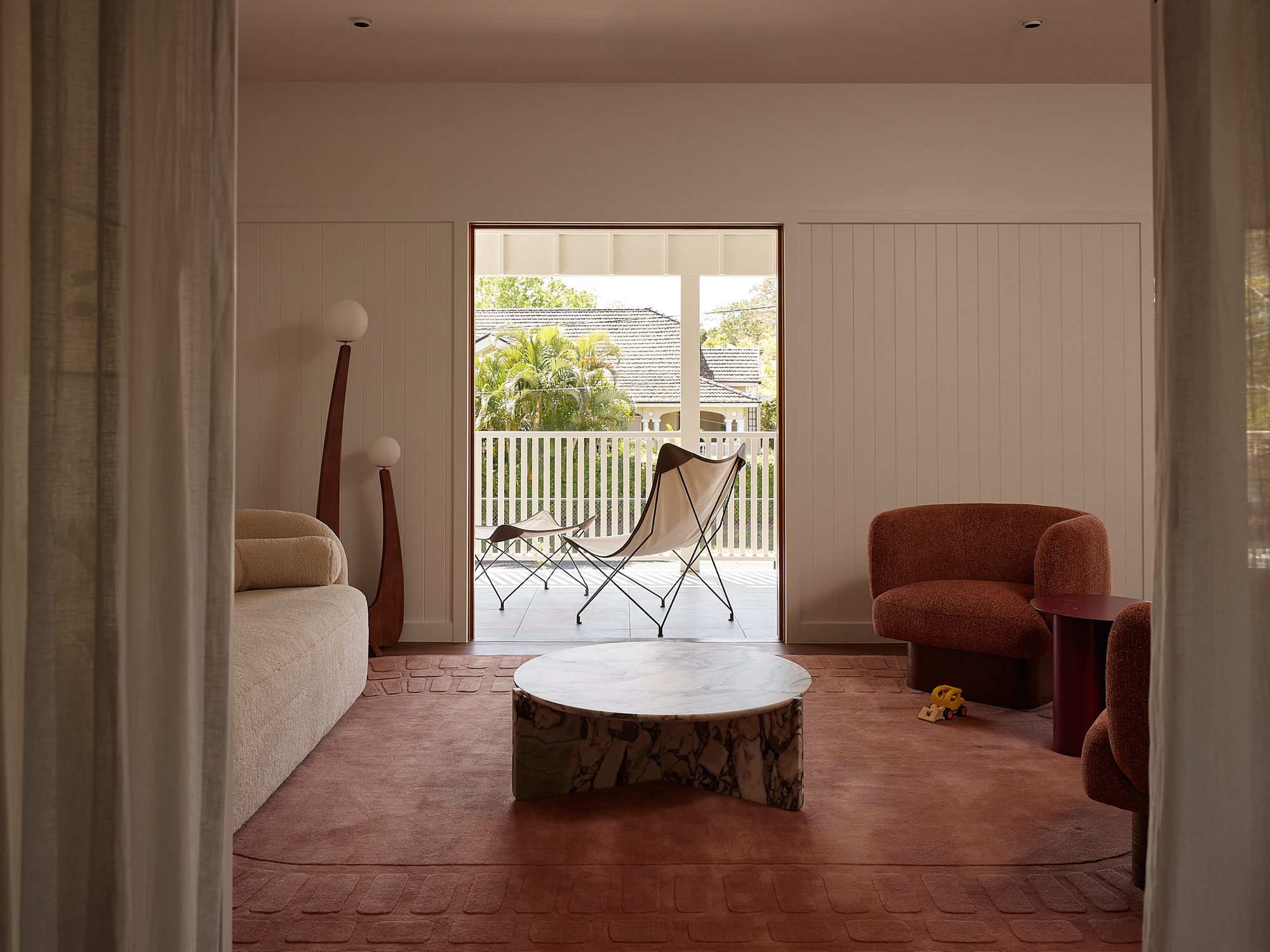 Living room with terracotta parquet floor opening to a timber-railed balcony under daylight