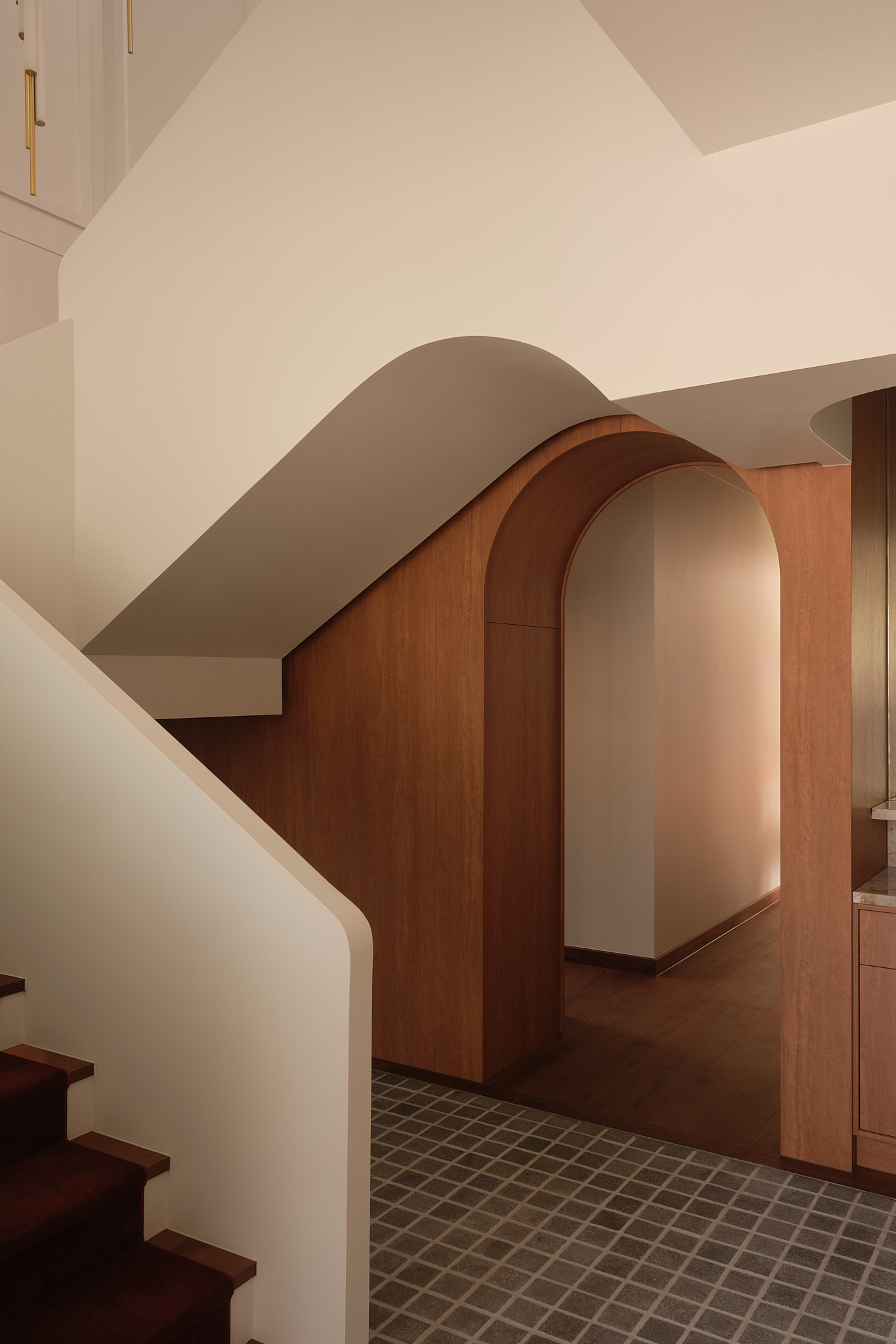 Arched timber portal framing a view through to a corridor and staircase beyond