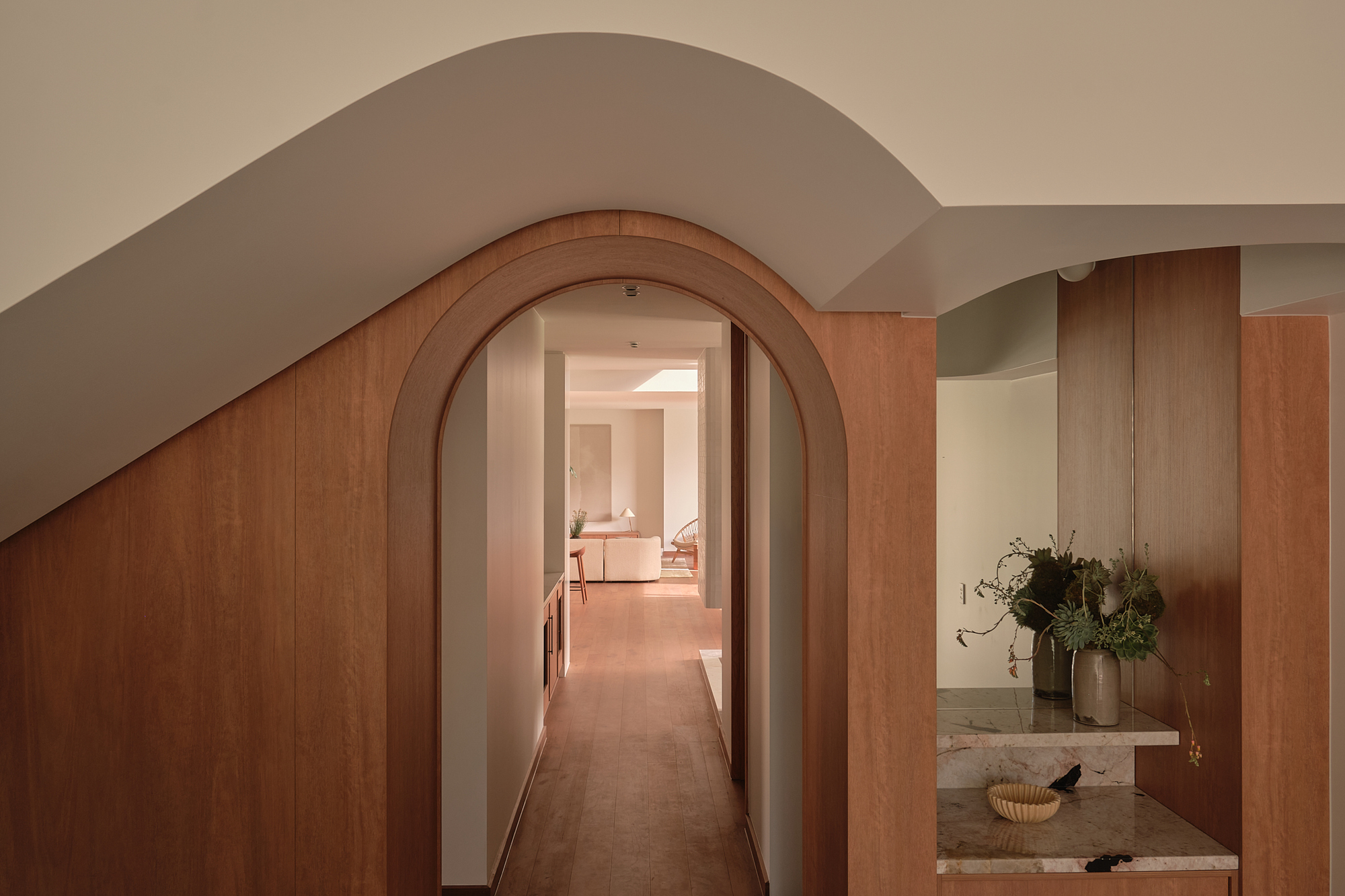 Timber-lined arched doorway leading to a corridor with a vanity niche visible to the right