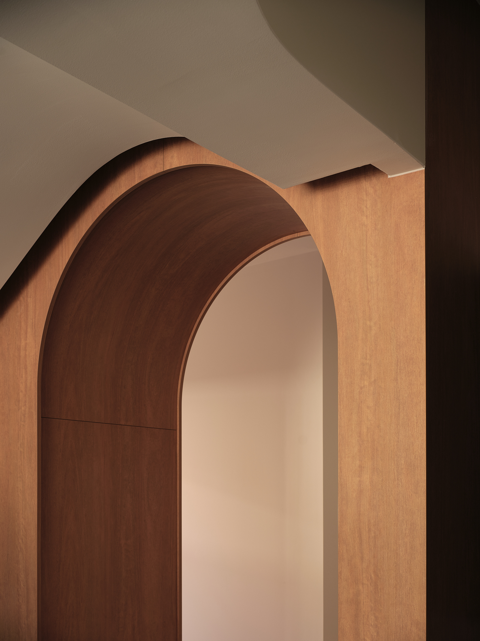 Close-up of the layered timber archway showing the curved veneer edges against white plaster