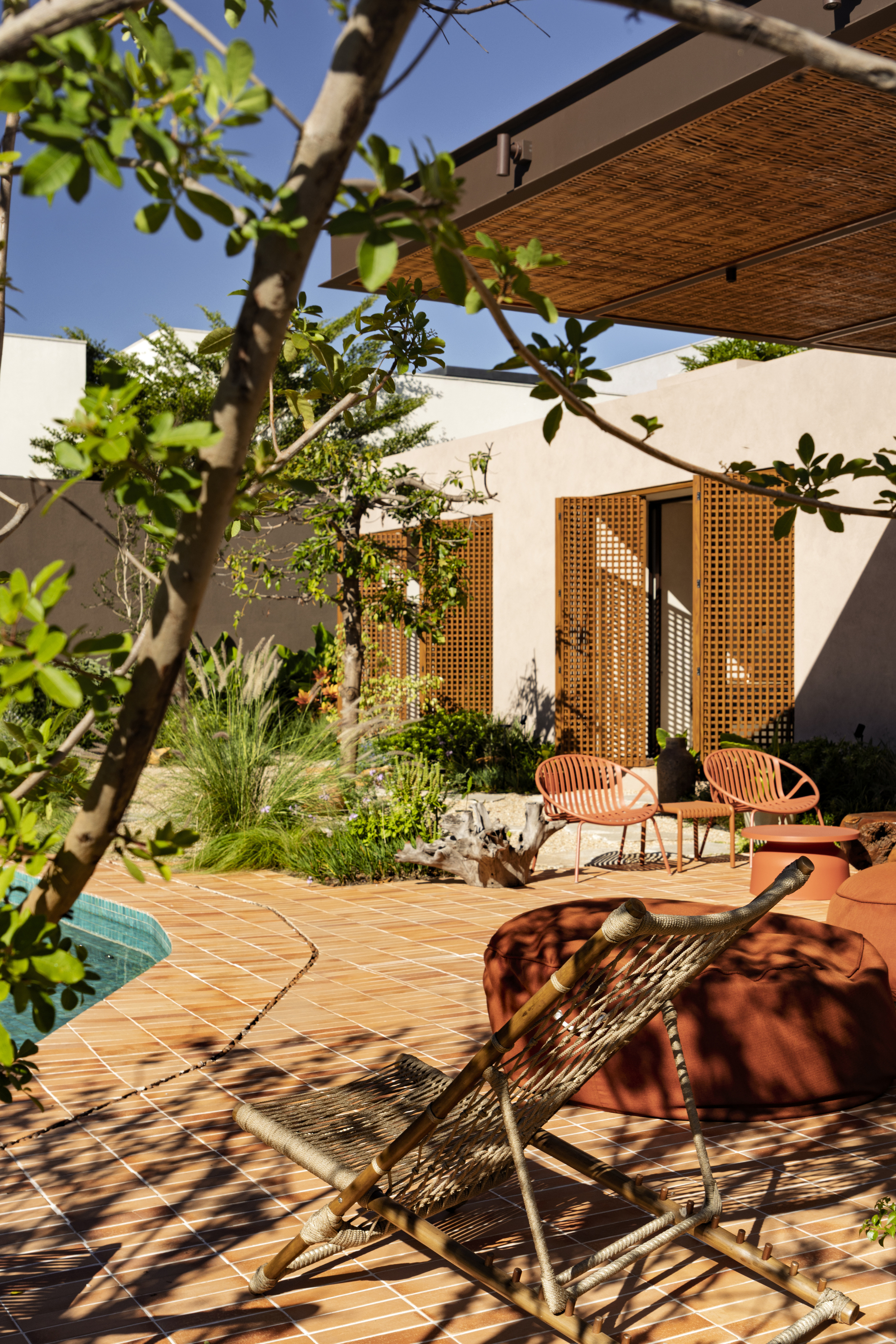 Interior courtyard with terracotta tile paving and mesh seating beneath fruit tree branches