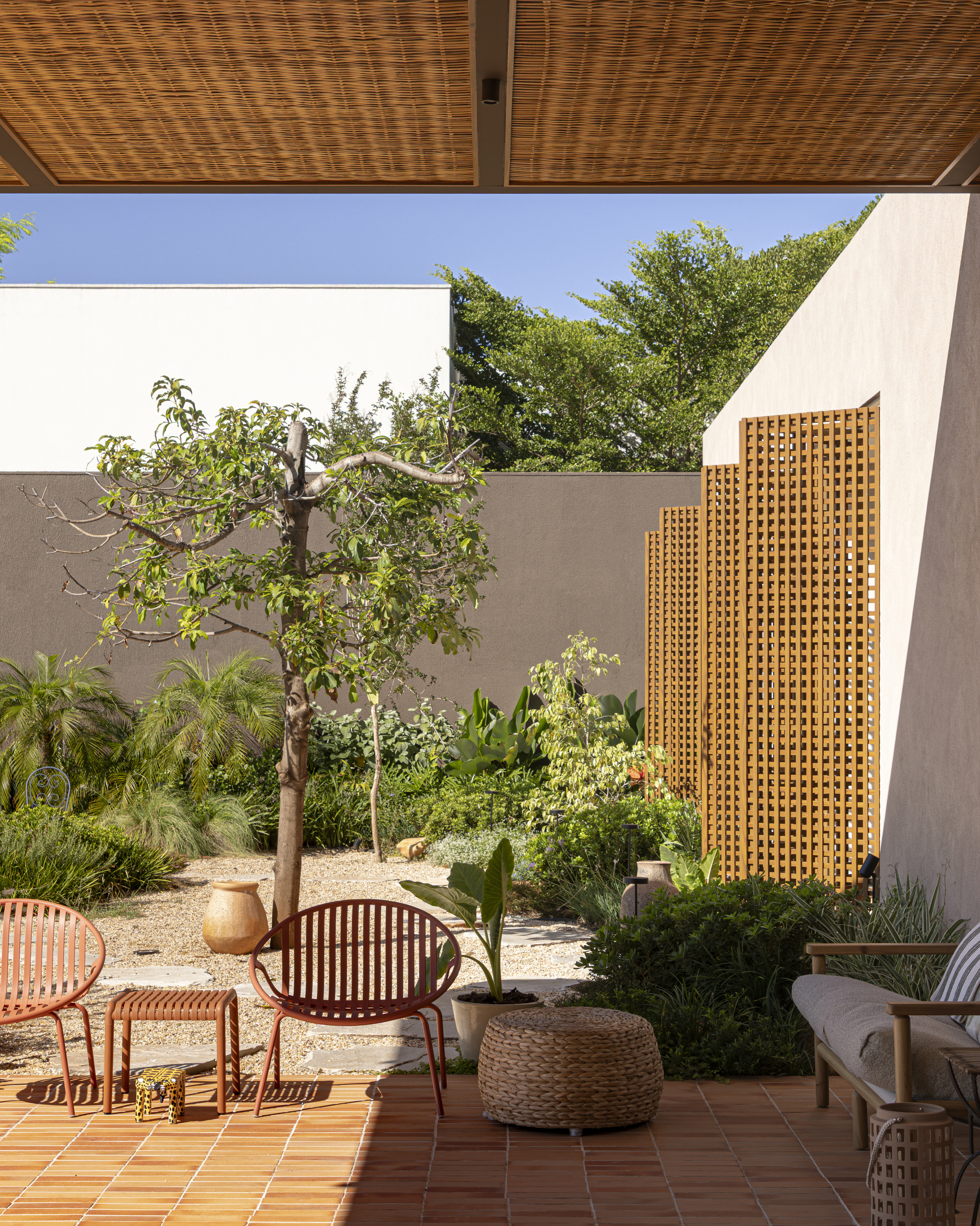 Enclosed courtyard with lattice screen and woven ceiling panel over terracotta tile terrace