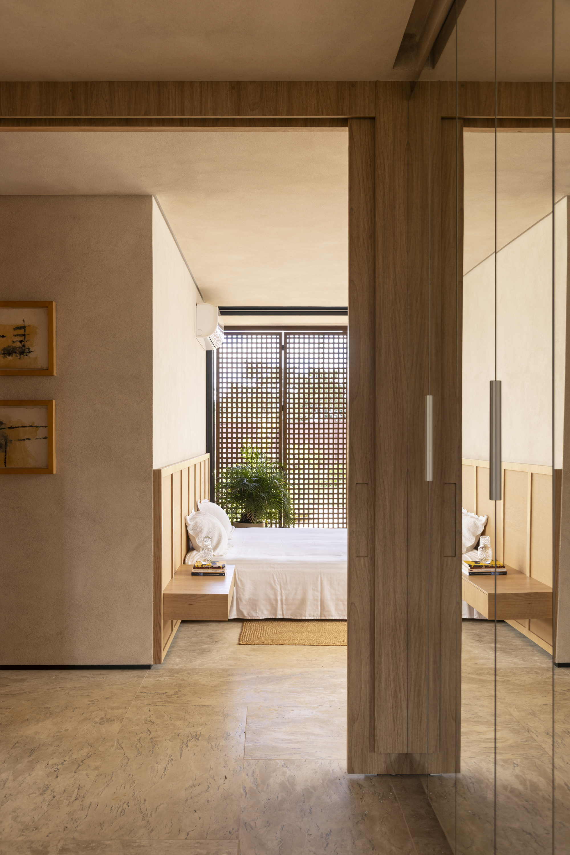 Interior corridor view through timber doorframe toward bedroom with gridded screen beyond