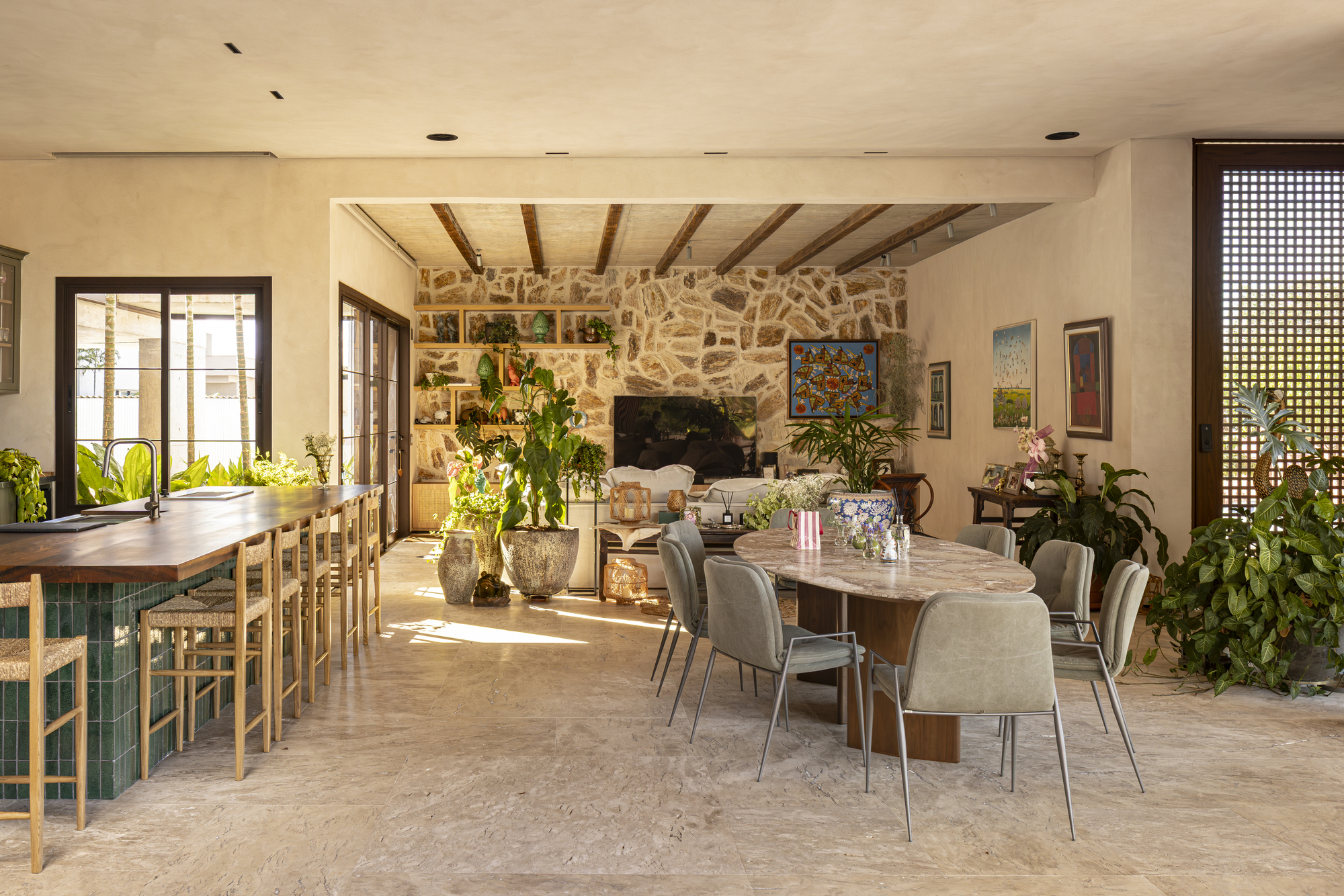Open living and dining room with stone fireplace wall and exposed timber ceiling beams