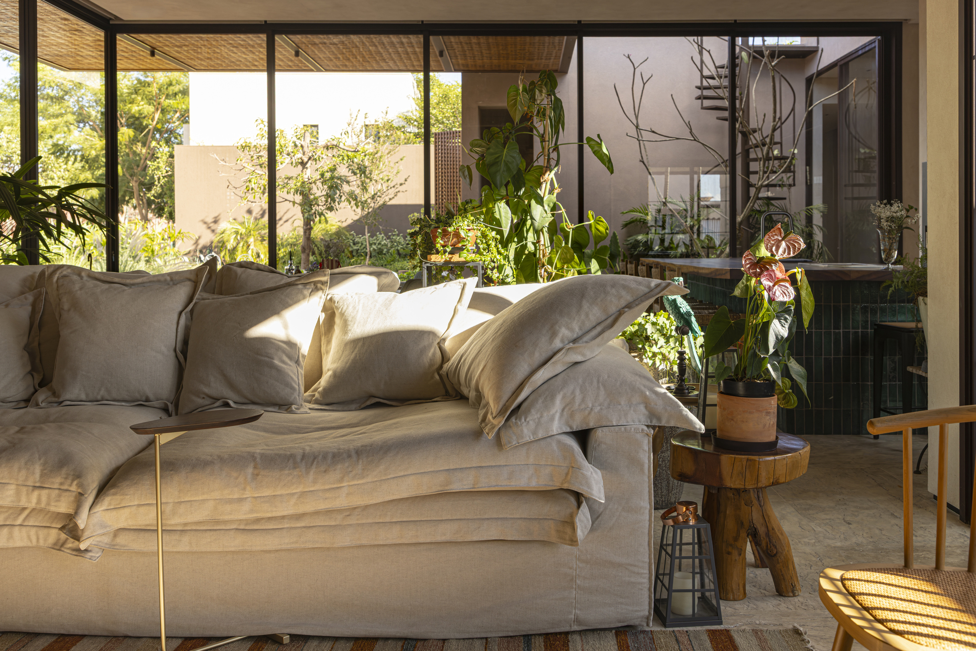 Living room with woven ceiling and full-height glazing opening to a planted interior courtyard